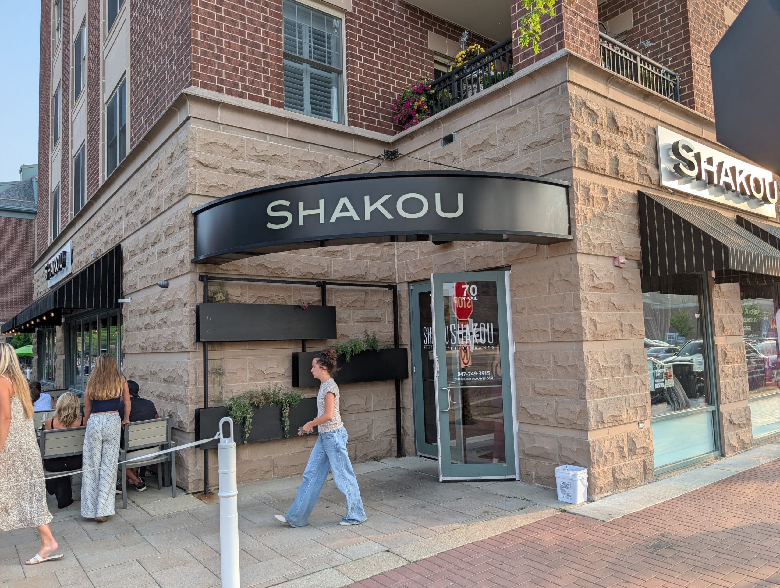 Shakou storefront on the corner of Vail Avenue in downtown Arlington Heights with black awnings and patio seating
