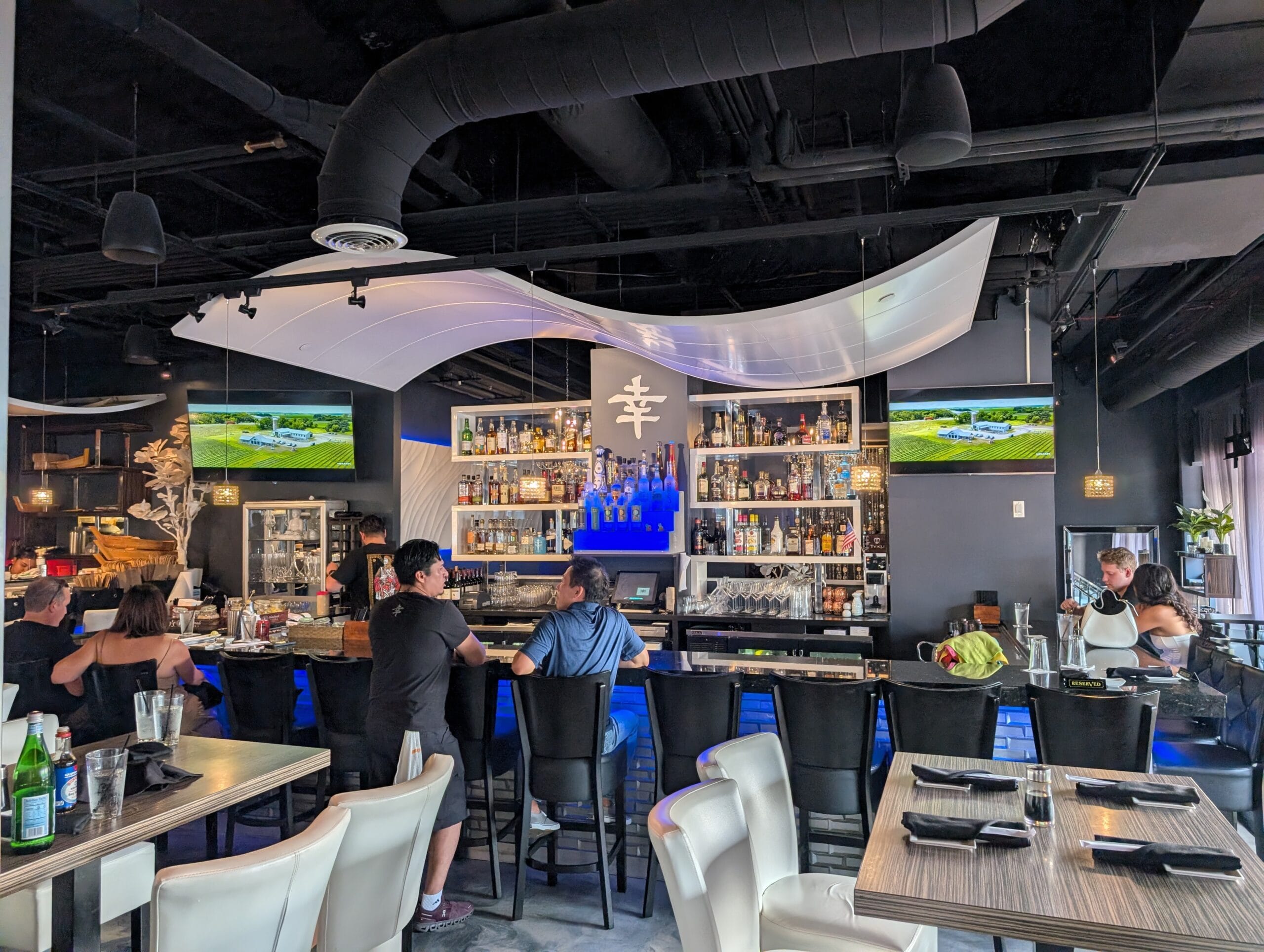 Backlit bar at Shakou Arlington Heights with blue lighting and a wave shaped ceiling sculpture