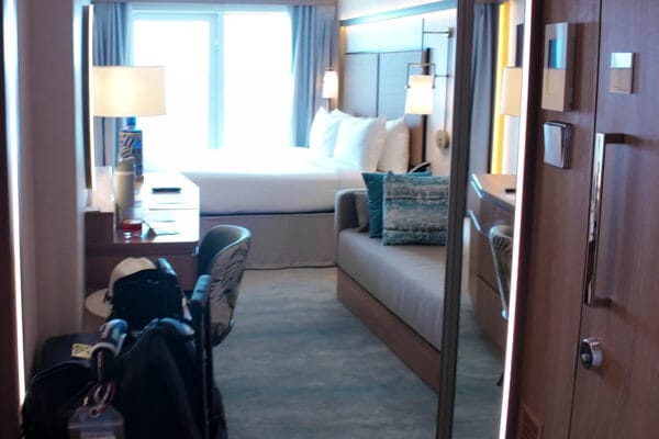 Walking into stateroom 14632 on Legend of the Seas, the couch on the right and the bed by the balcony window