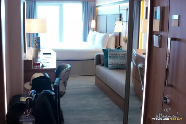 Walking into stateroom 14632 on Legend of the Seas, the couch on the right and the bed by the balcony window