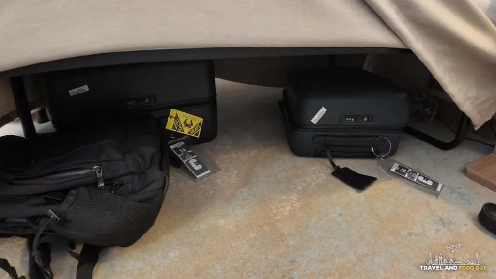 Full size suitcases and shoes stored under the raised bed in a Legend of the Seas stateroom