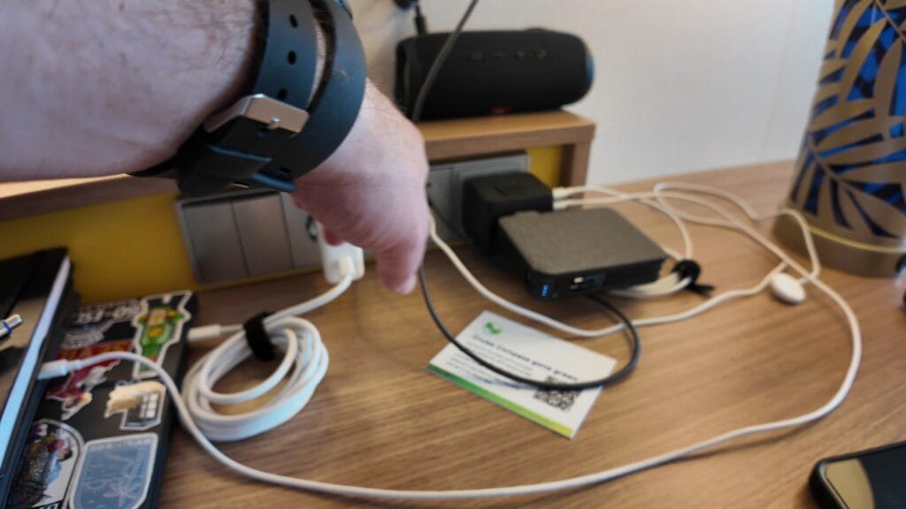 Charging cords, a USB splitter and a power inverter set up on the desk in a cruise stateroom