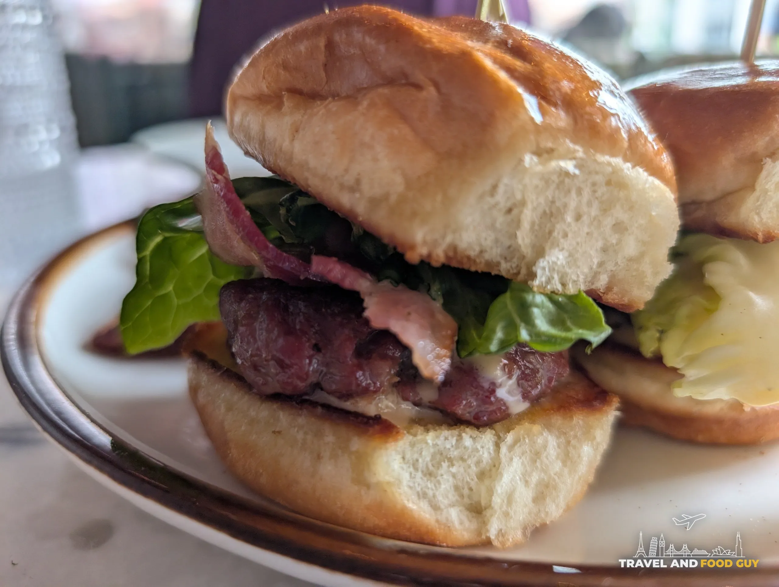 A close look at one Ambar slider, smoked gouda melting over the beef with bacon, pickled red onion and lettuce on a brioche bun.