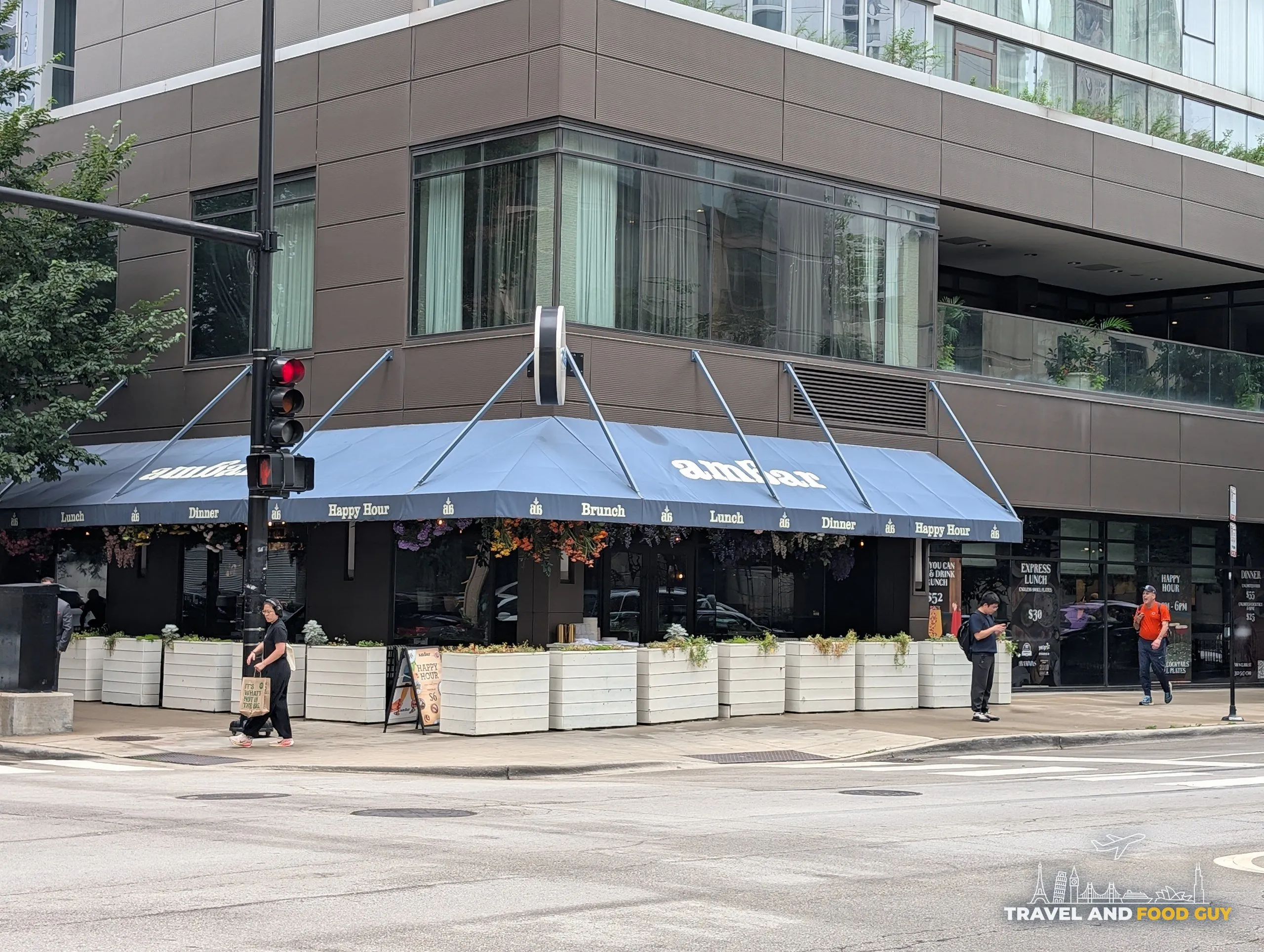 The wraparound blue awning lists lunch, dinner, brunch and happy hour, with the unlimited pricing board mounted beside the entrance.