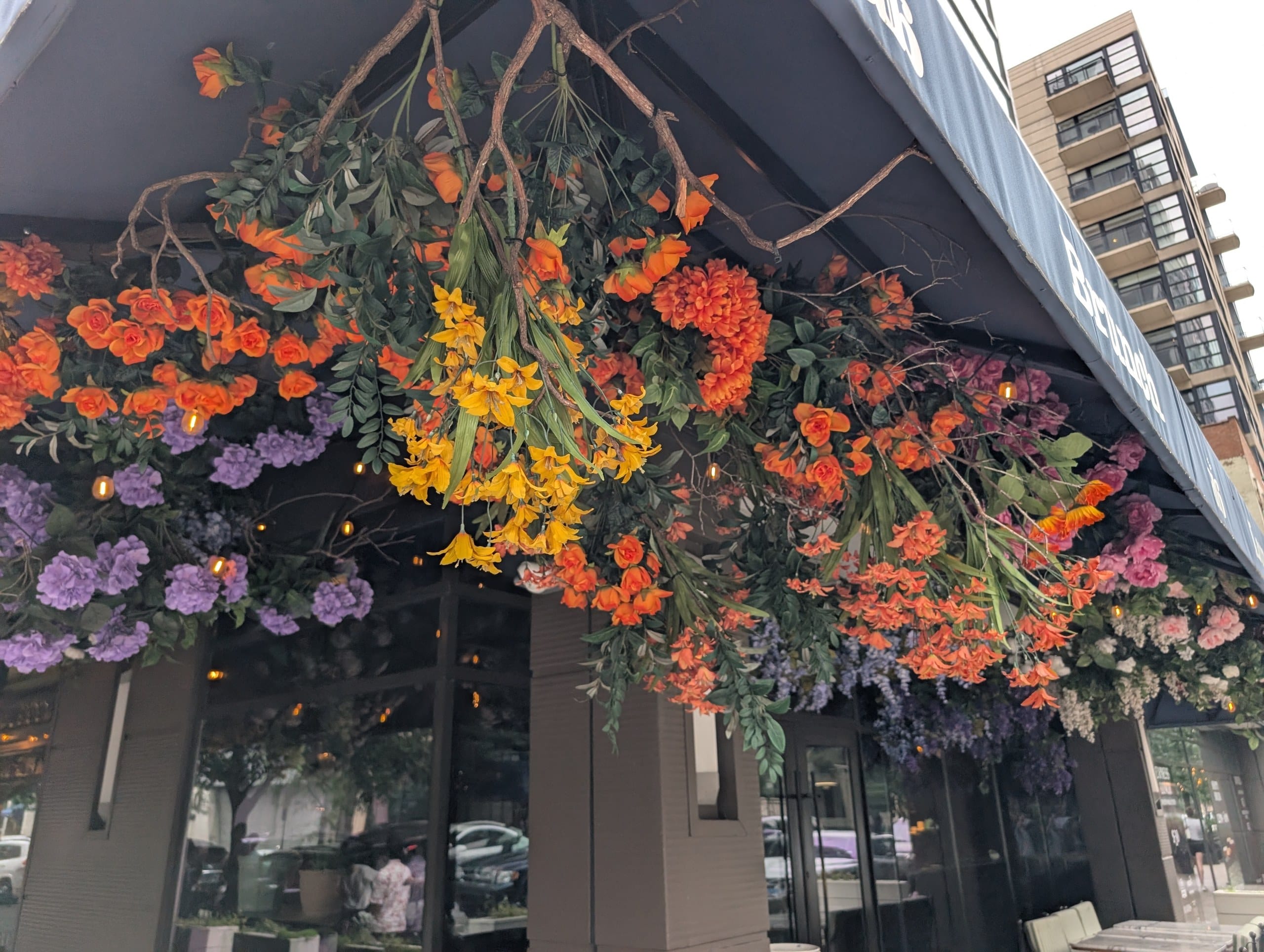 Cascading orange, purple and yellow faux blooms line the underside of the awning above the corner patio seating.