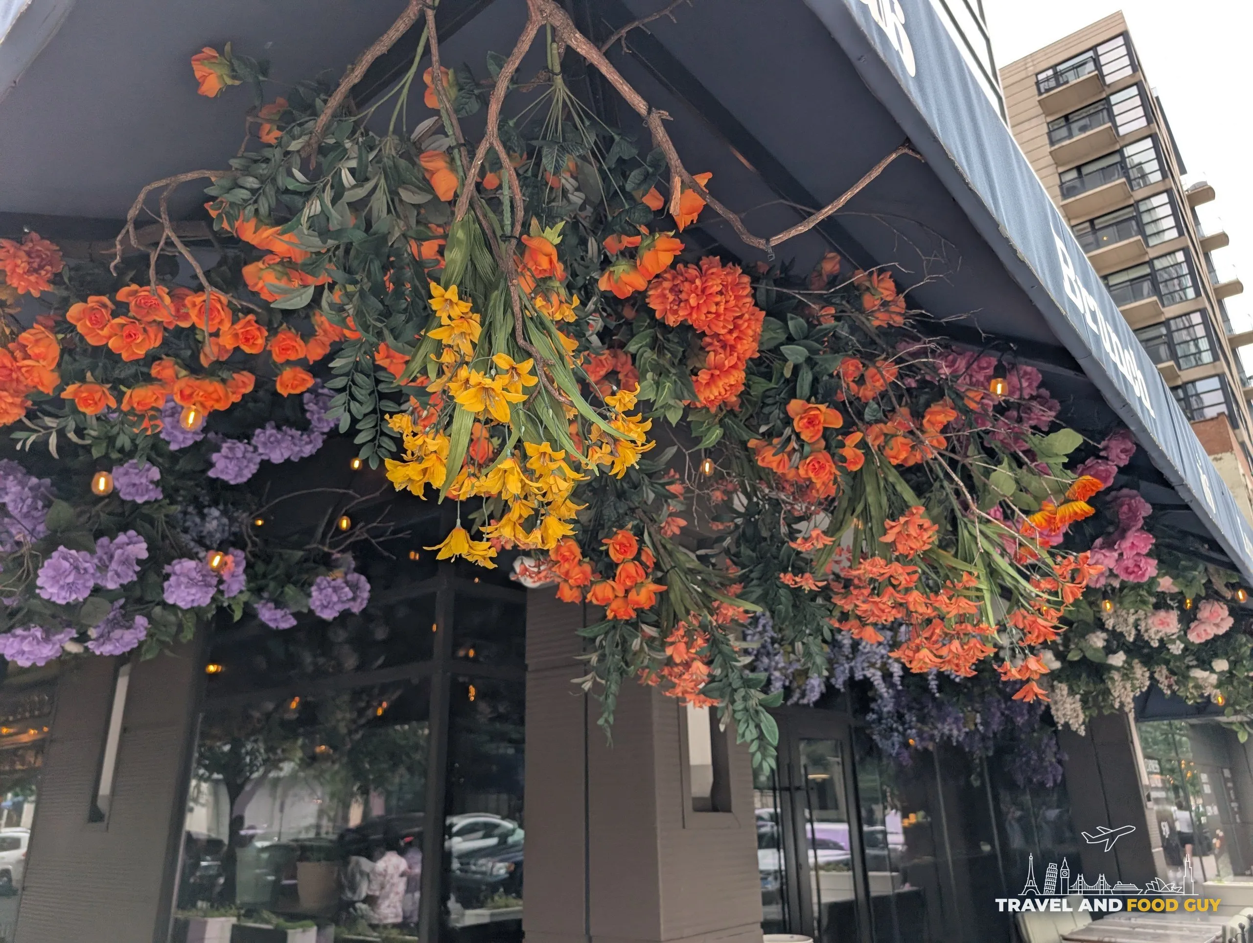 Cascading orange, purple and yellow faux blooms line the underside of the awning above the corner patio seating.