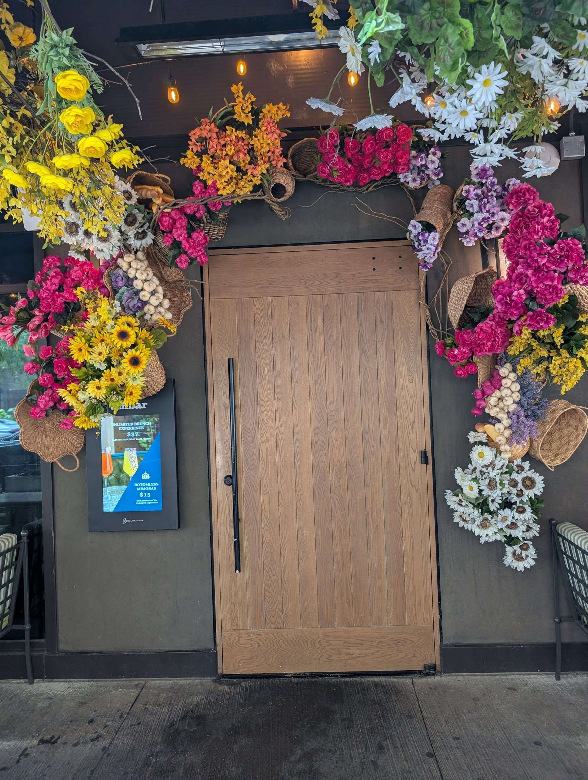 The oak front door is framed by baskets of sunflowers, roses and garlic braids, with the bottomless brunch board posted to the left.