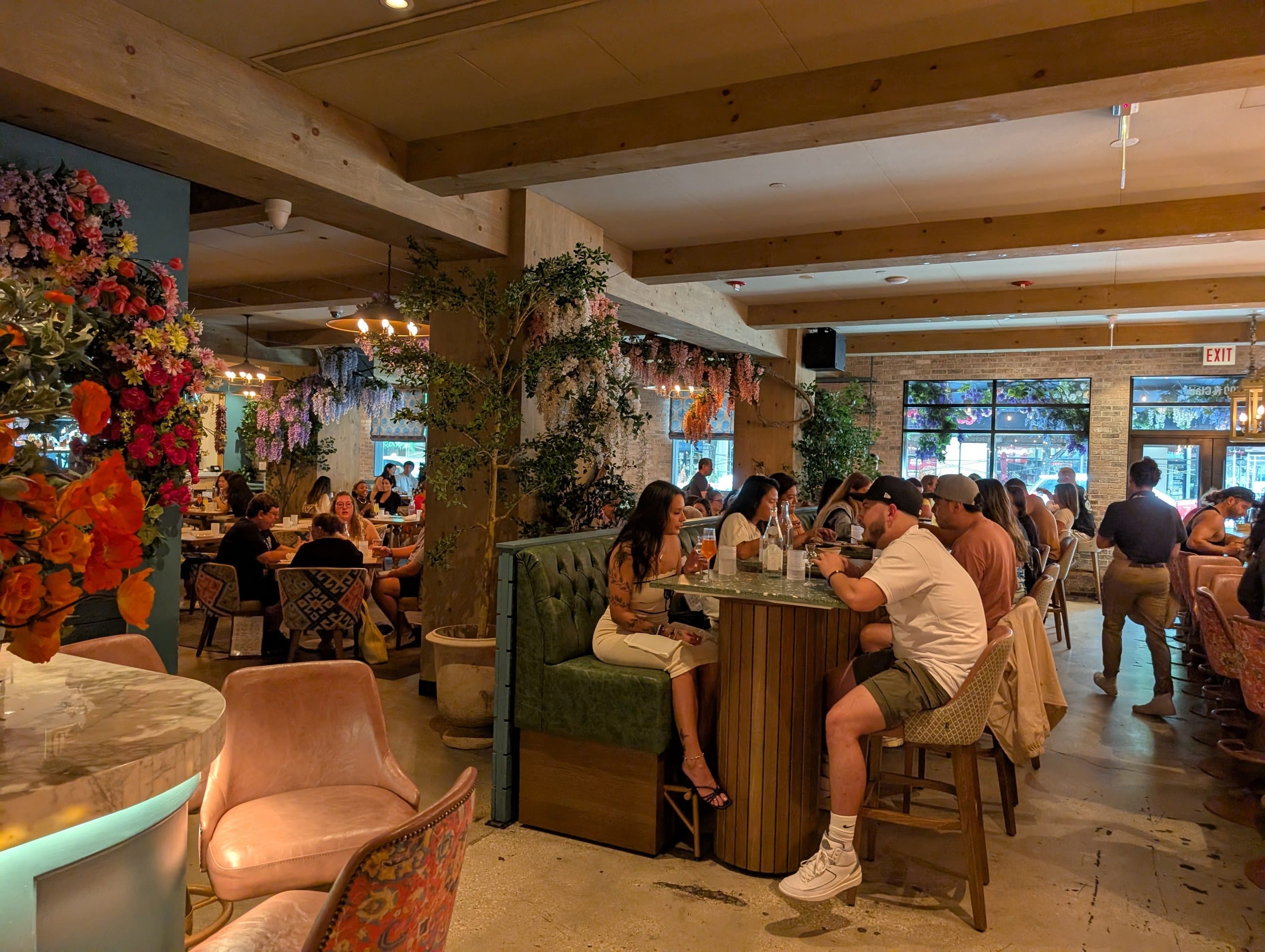 Blush velvet lounge chairs and a marble topped bar sit at the front of the main room, with high tops and banquettes filling the space behind.