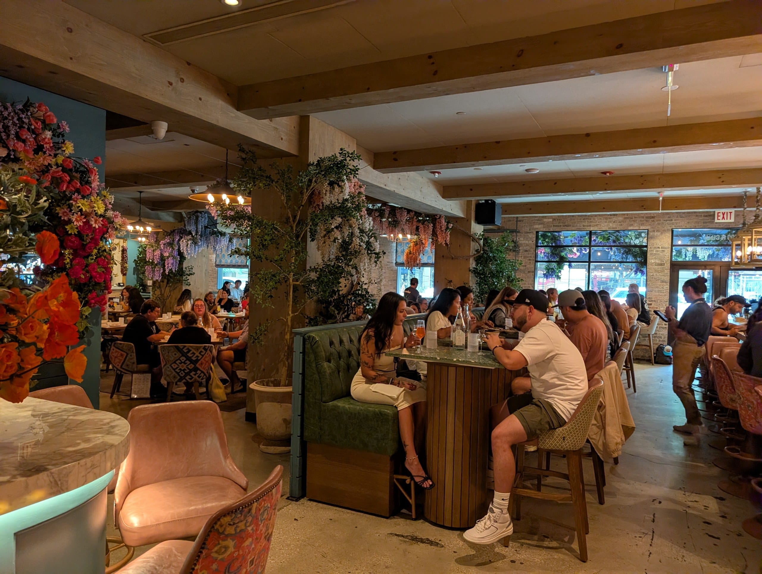 The main room runs deep with timber beams, hanging greenery and wisteria, a green banquette bar table in the middle and windows onto Clark Street.