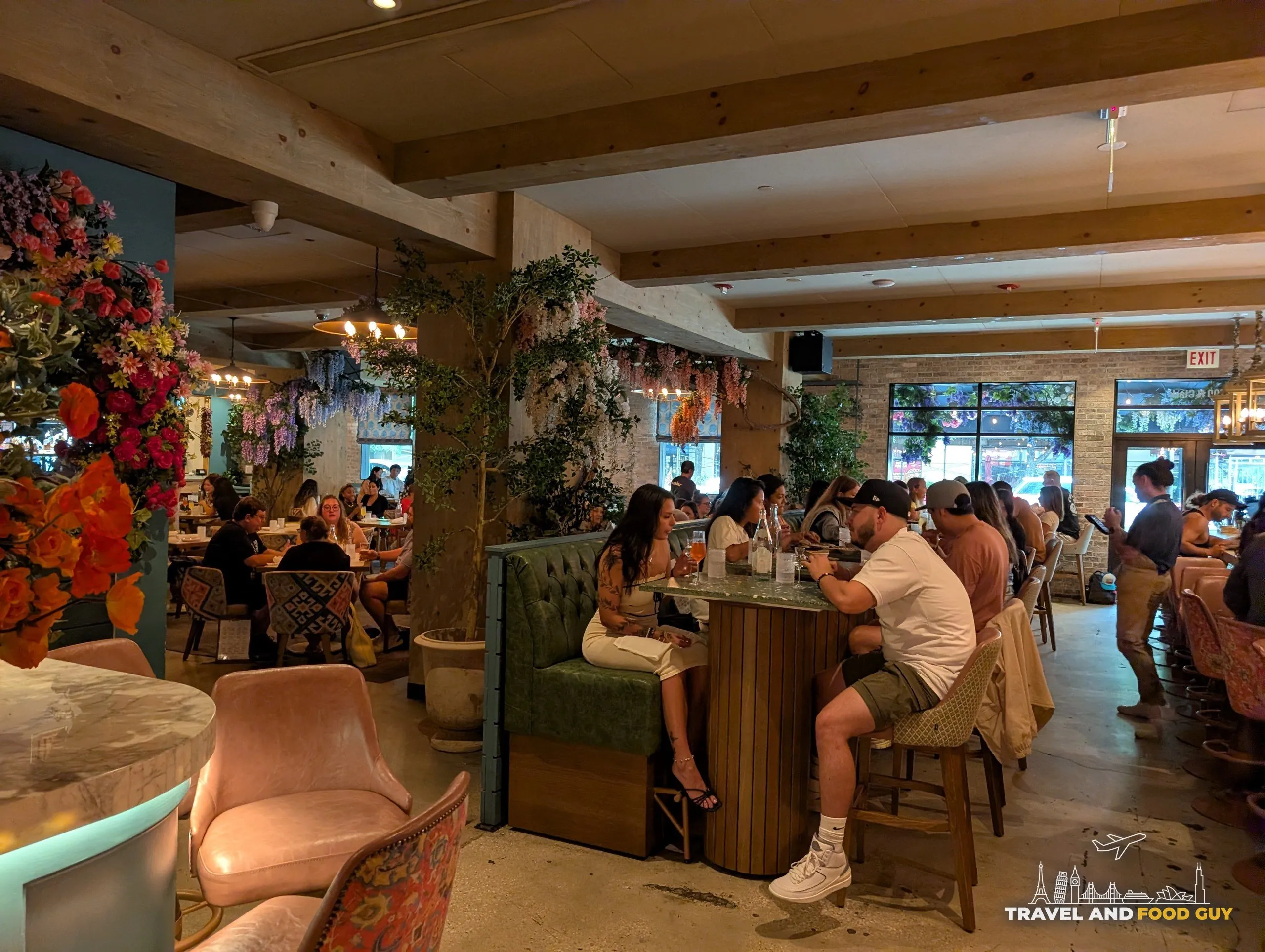 The main room runs deep with timber beams, hanging greenery and wisteria, a green banquette bar table in the middle and windows onto Clark Street.
