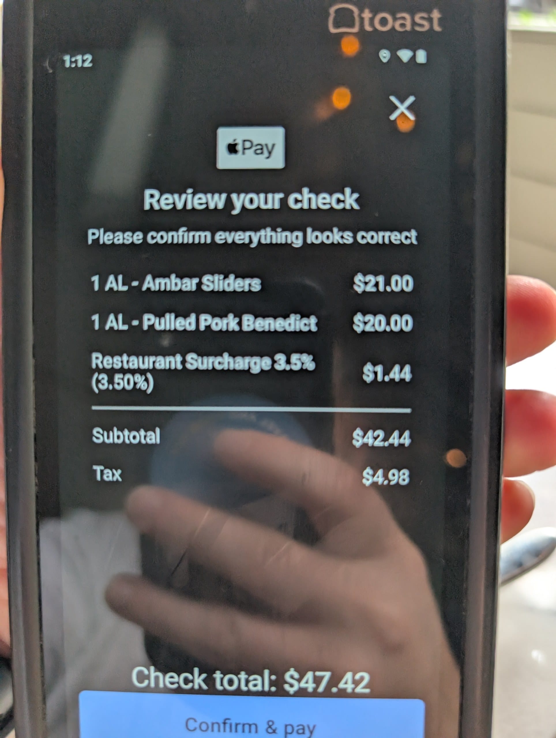 The check shows two a la carte plates, Ambar sliders at twenty one dollars and pulled pork benedict at twenty, a three and a half percent restaurant surcharge, and a total of forty seven dollars and forty two cents.