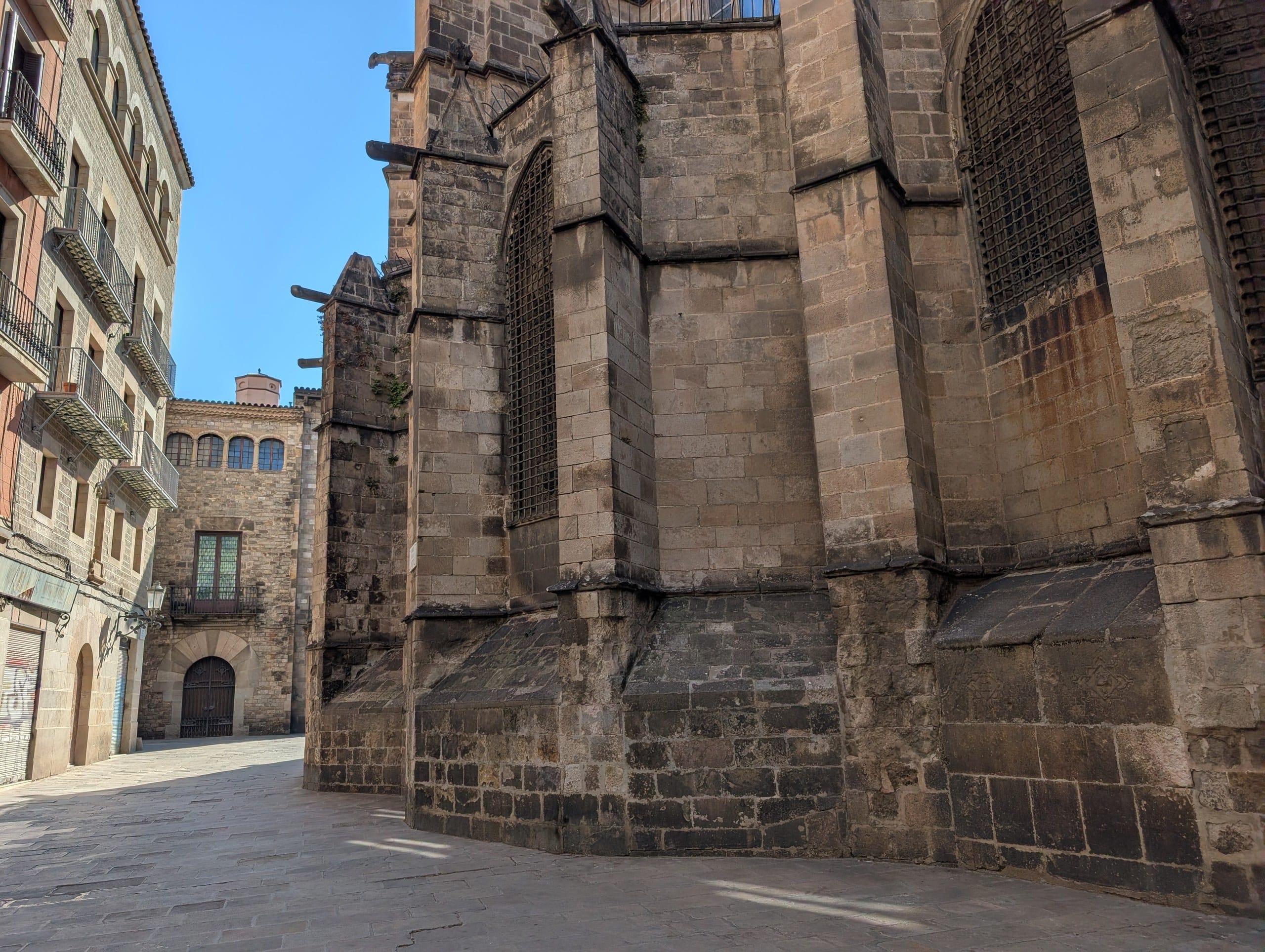 The stone apse of Barcelona Cathedral seen from a small square in the Gothic Quarter