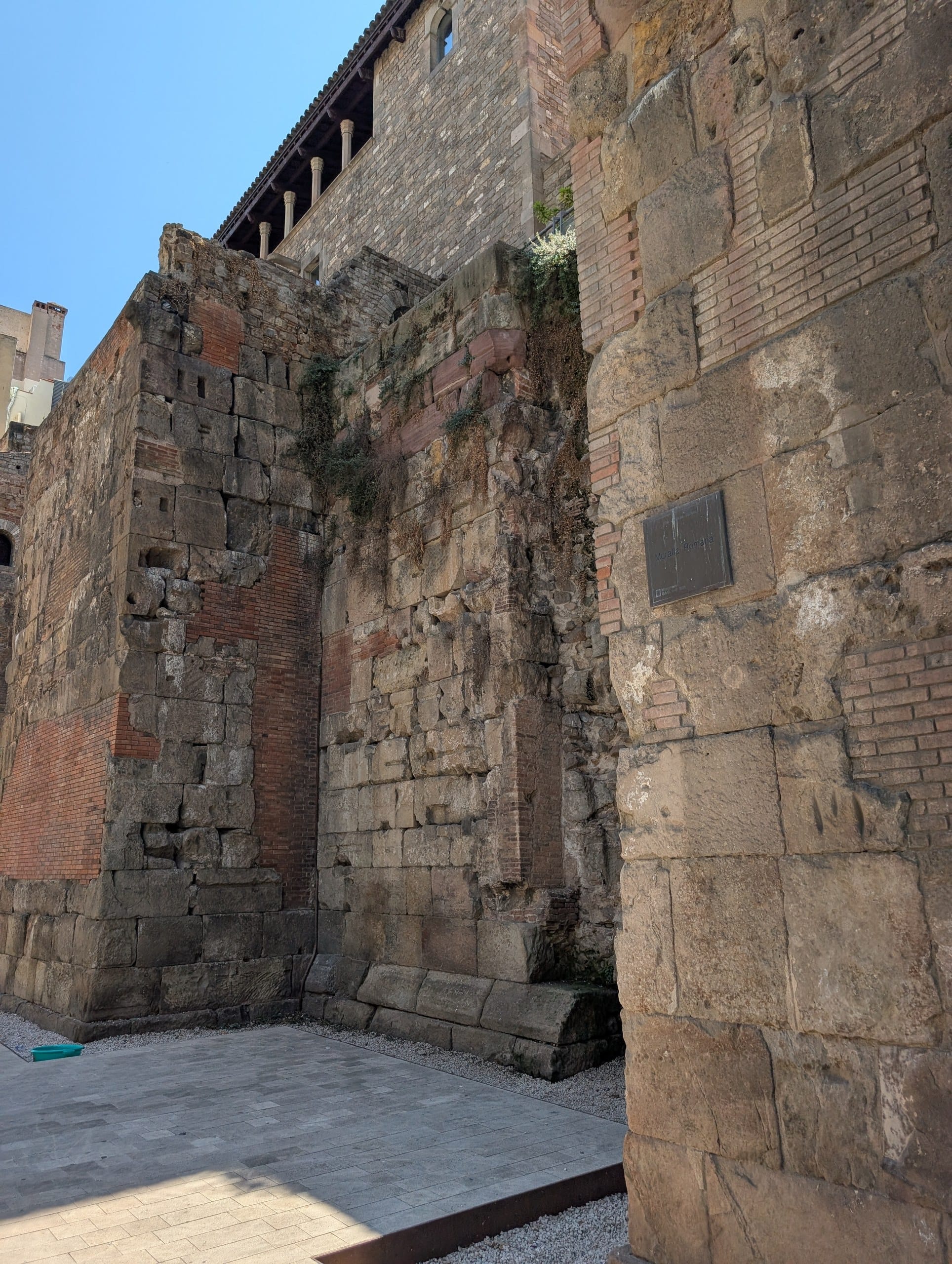 A dark metal plaque reading Muralla Romana fixed to a block of the Roman city wall in Barcelona