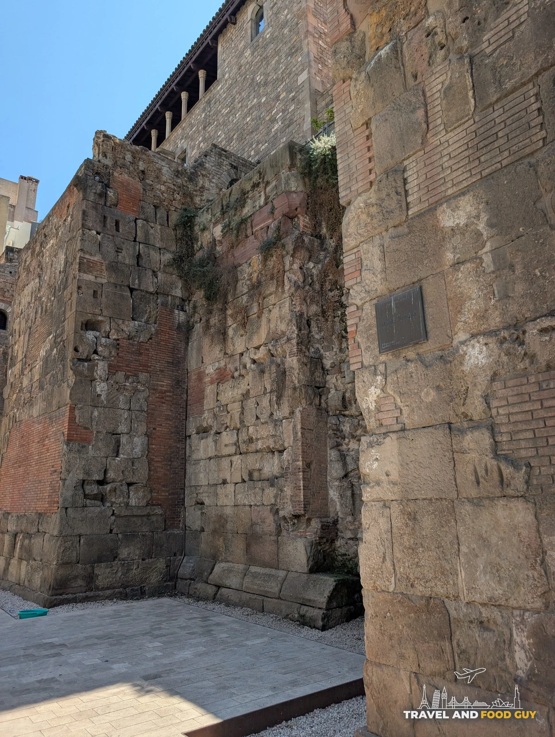 A dark metal plaque reading Muralla Romana fixed to a block of the Roman city wall in Barcelona