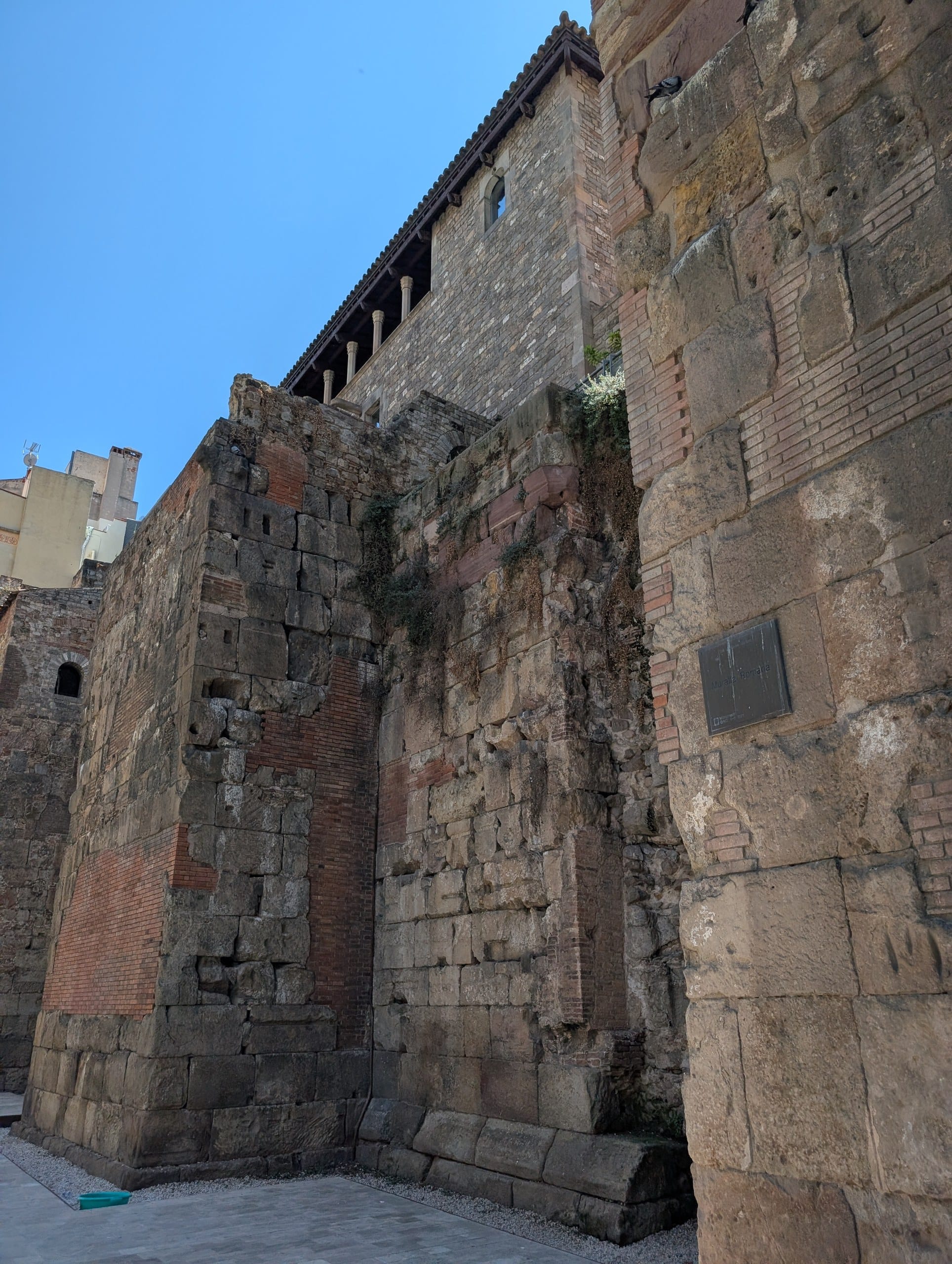 A tall stretch of the Roman city wall of Barcelona with a medieval gallery built on top of it