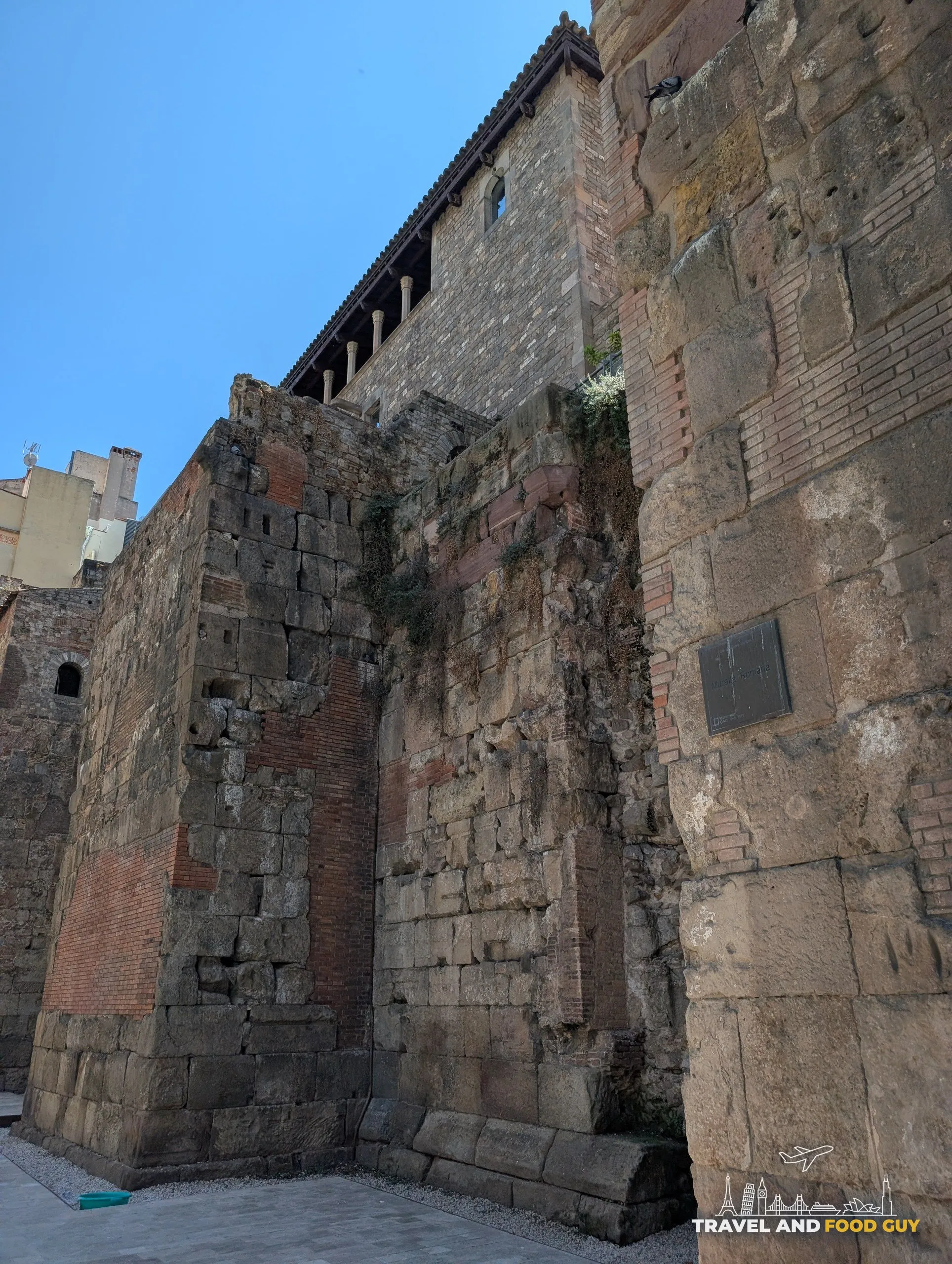 A tall stretch of the Roman city wall of Barcelona with a medieval gallery built on top of it