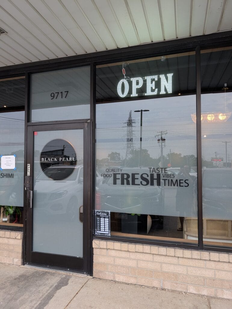 The front door at 9717, with the lit OPEN sign and the QUALITY FOOD FRESH TASTE window decal.