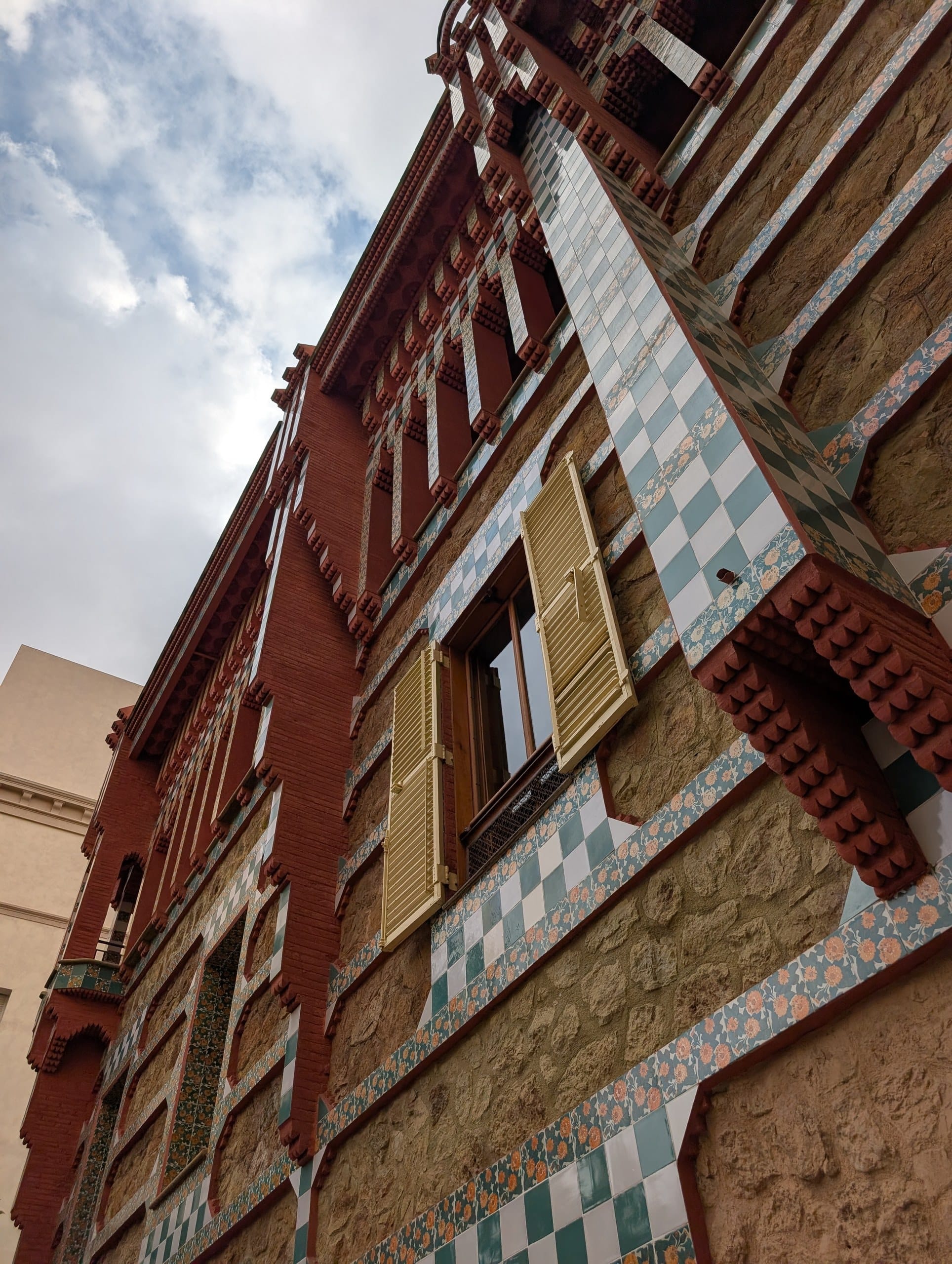 Looking up the Casa Vicens facade at checkerboard tile and yellow shutters