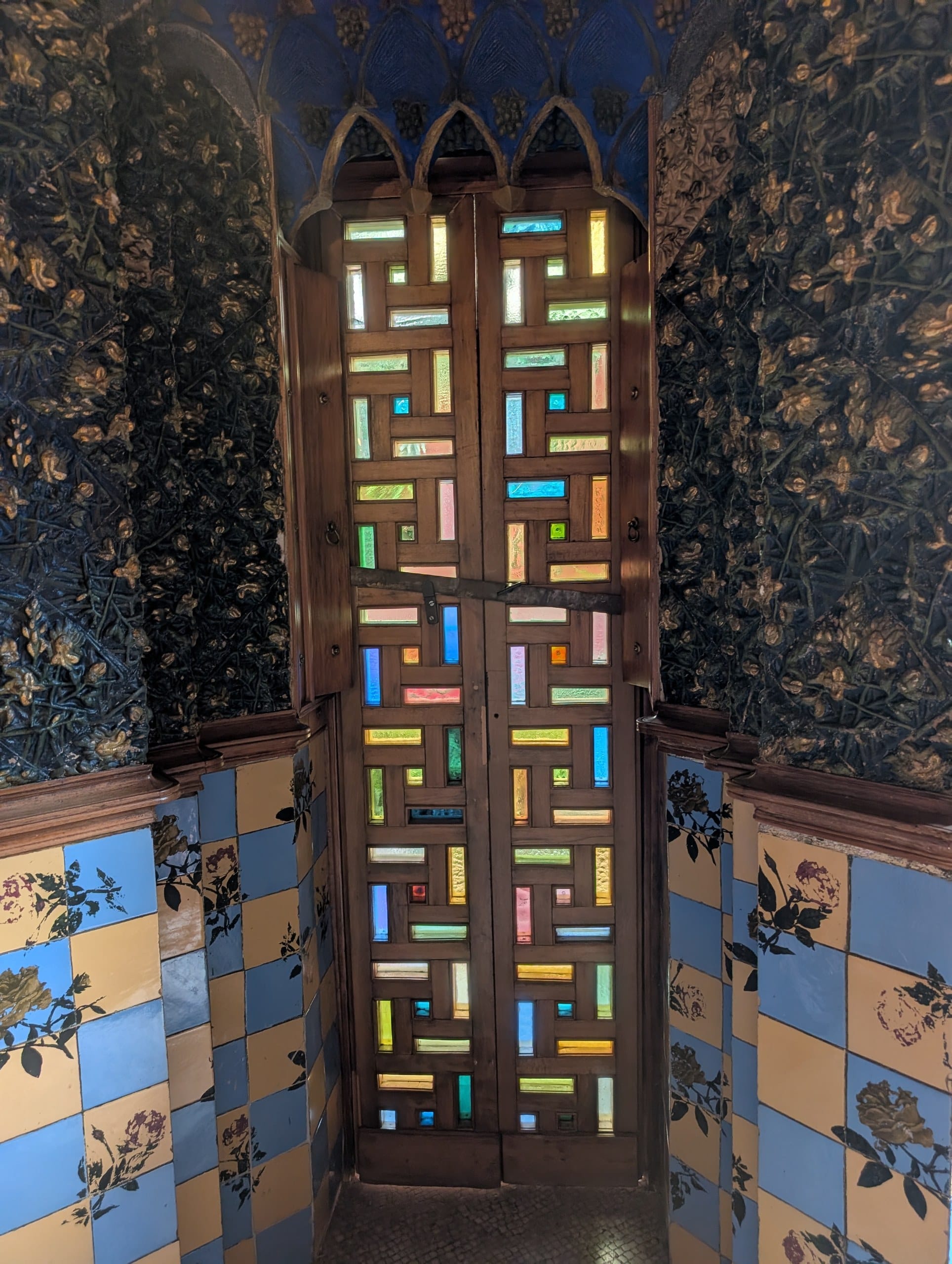 Stained glass doors against painted floral walls inside Casa Vicens