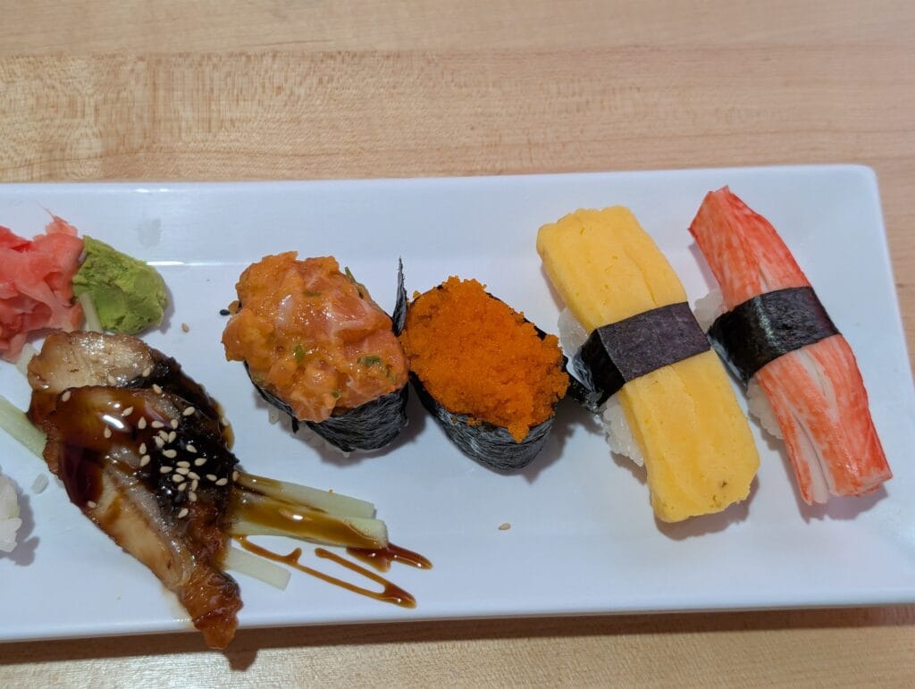 A round of nigiri at e Sushi: two pieces of glazed eel, a spicy salmon gunkan, a masago gunkan, tamago and crab stick, with pickled ginger and wasabi.