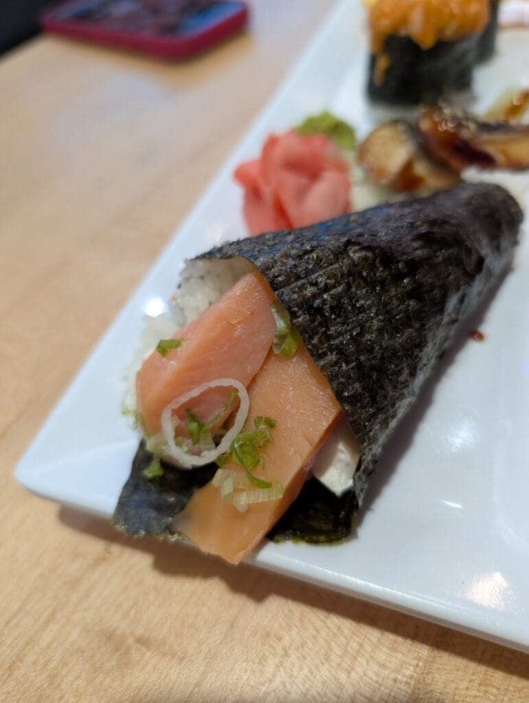 The Philadelphia at e Sushi, ordered as a hand roll: smoked salmon and cream cheese in a nori cone with scallion and raw onion.