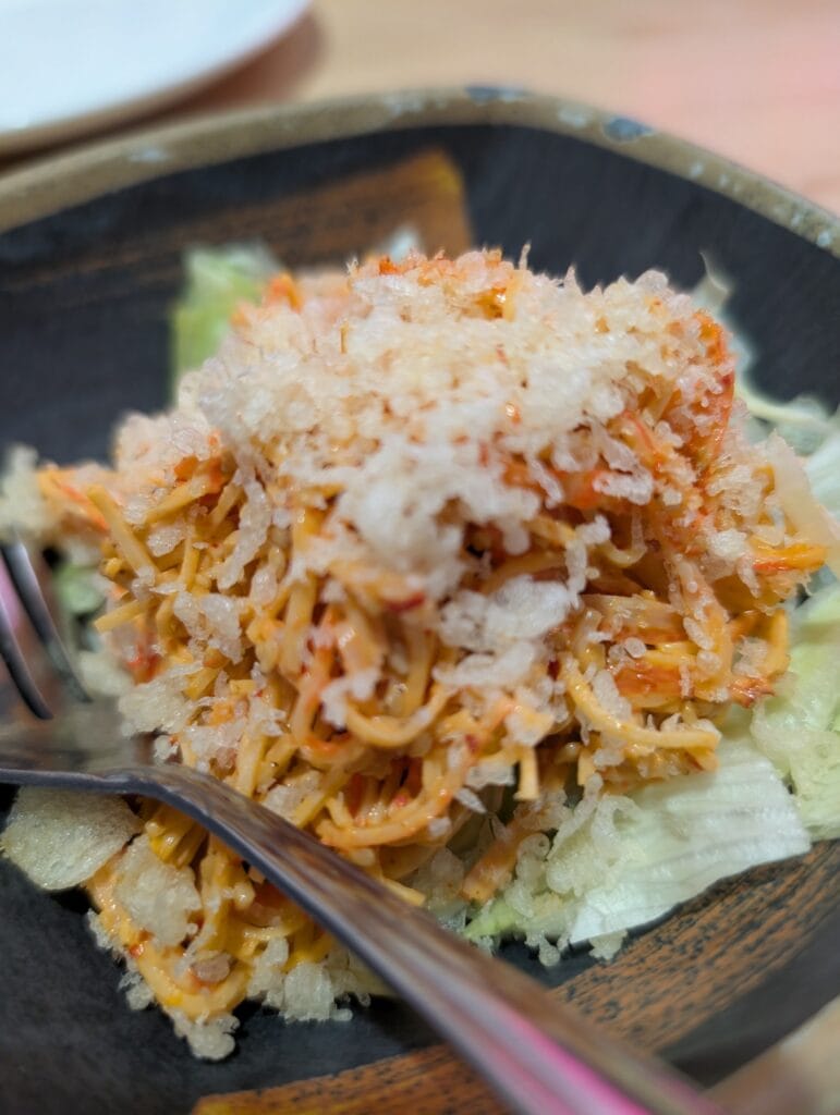 The spicy kani salad at e Sushi, shredded crab stick in an orange dressing over iceberg lettuce, under a heavy layer of tempura crunch.