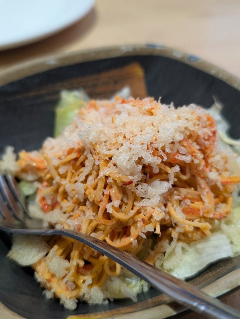 Close up on the spicy kani salad at e Sushi, where the tempura crunch has soaked into the dressing rather than sitting crisp on top.