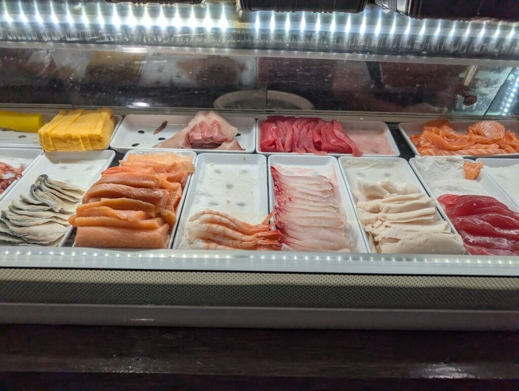 The chilled case behind the sushi bar at e Sushi, with trays of tamago, white tuna, tuna, salmon, mackerel, shrimp, red snapper and squid.