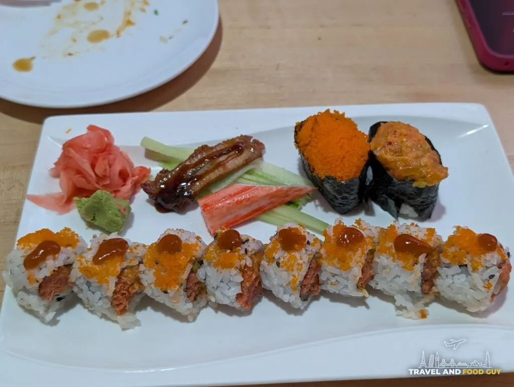 The Volcano roll at e Sushi, rice outside with spicy tuna in the middle, dusted with tobiko and sesame and dotted with chili sauce, plated with eel, crab stick and gunkan.