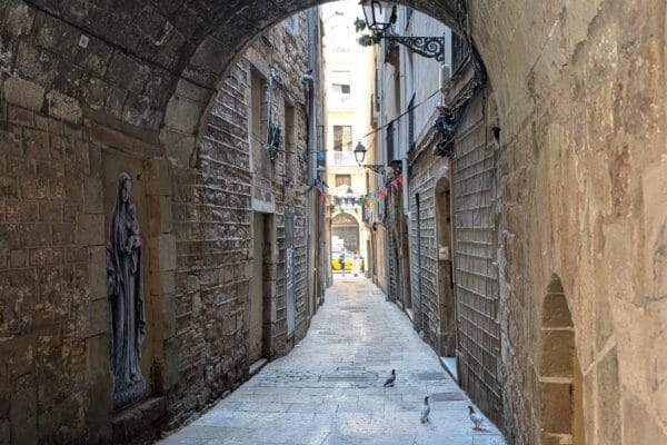 A stone arch spanning a narrow shaded lane in El Call, the medieval Jewish quarter of Barcelona