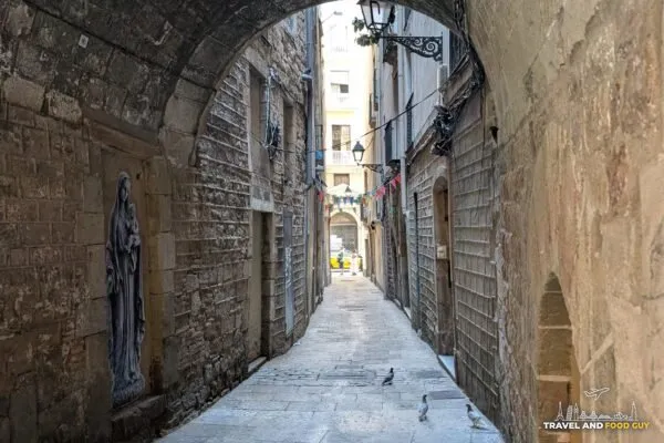 A stone arch spanning a narrow shaded lane in El Call, the medieval Jewish quarter of Barcelona
