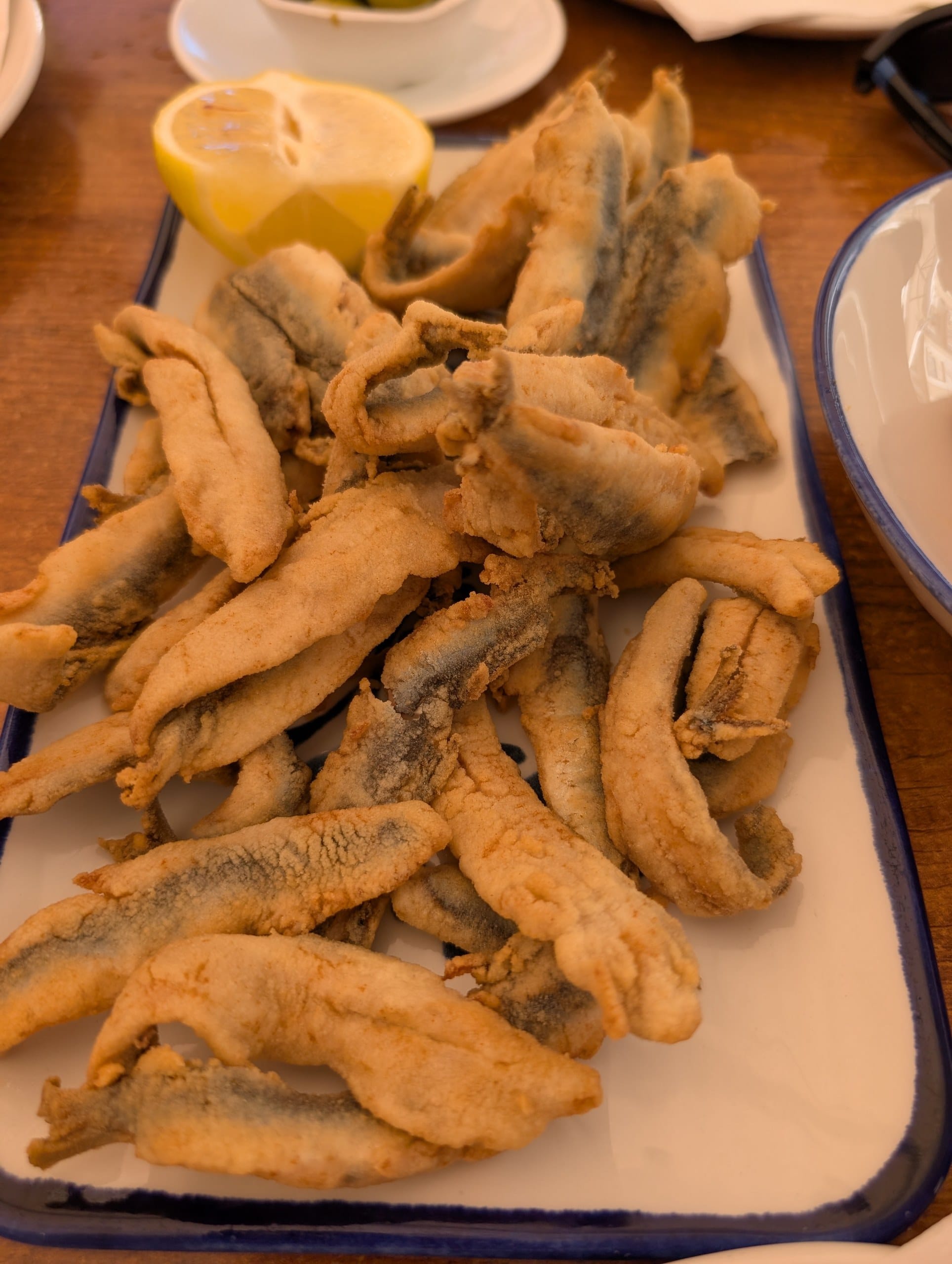 Platter of floured and fried whole anchovies with a lemon half at El Pimpi in Málaga