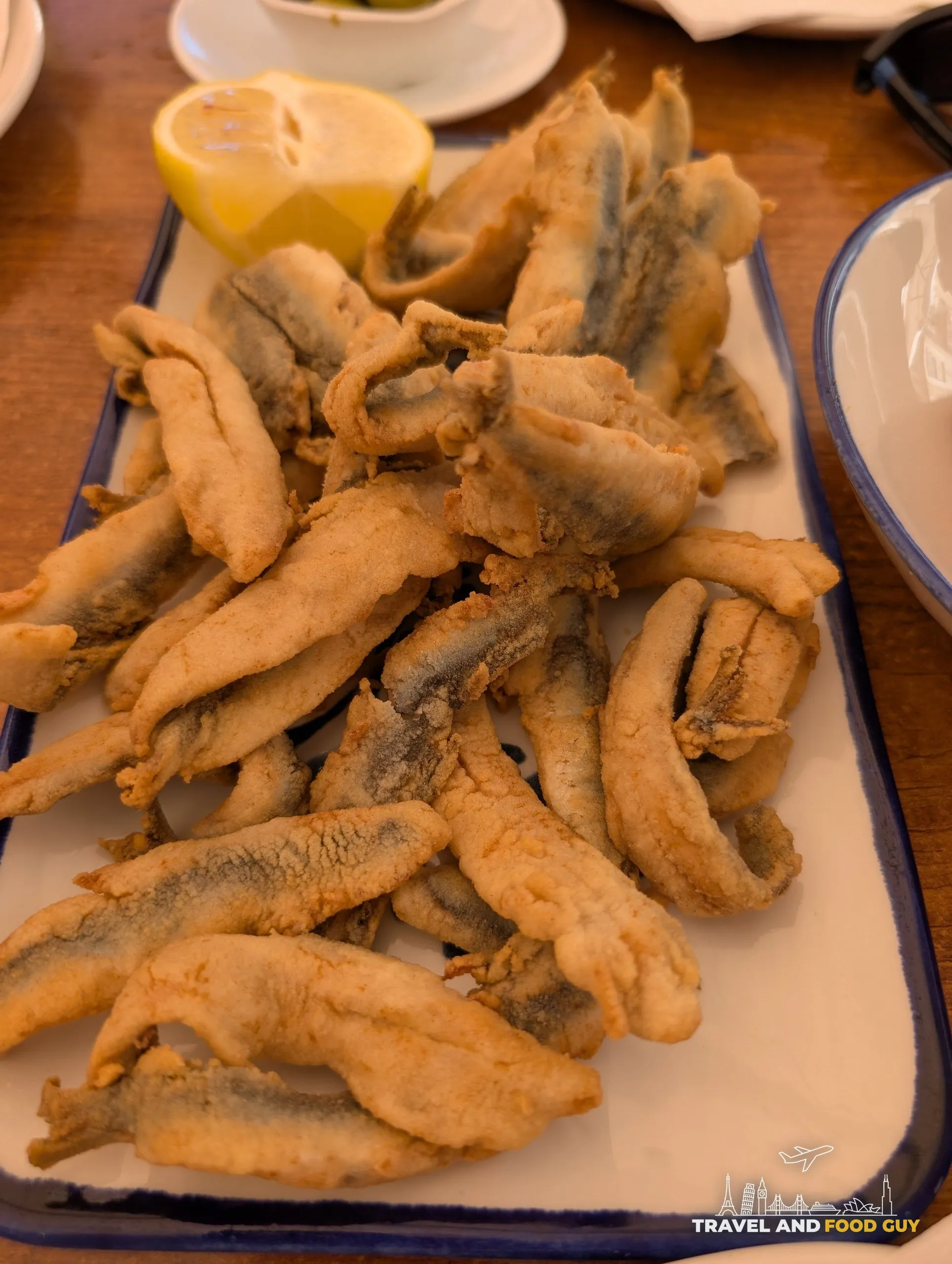 Platter of floured and fried whole anchovies with a lemon half at El Pimpi in Málaga
