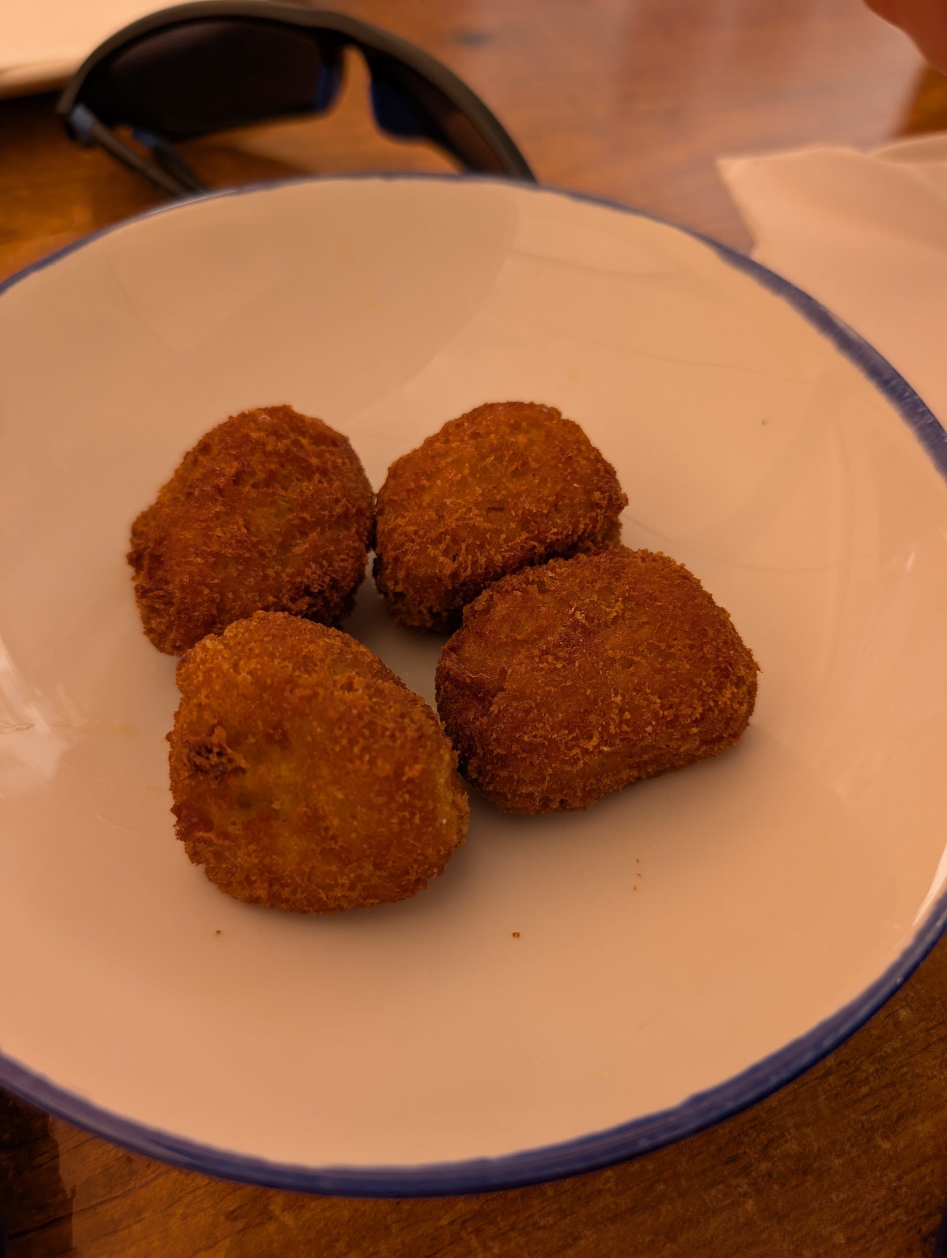 Four prawn croquettes in a white bowl with a blue rim at El Pimpi in Málaga