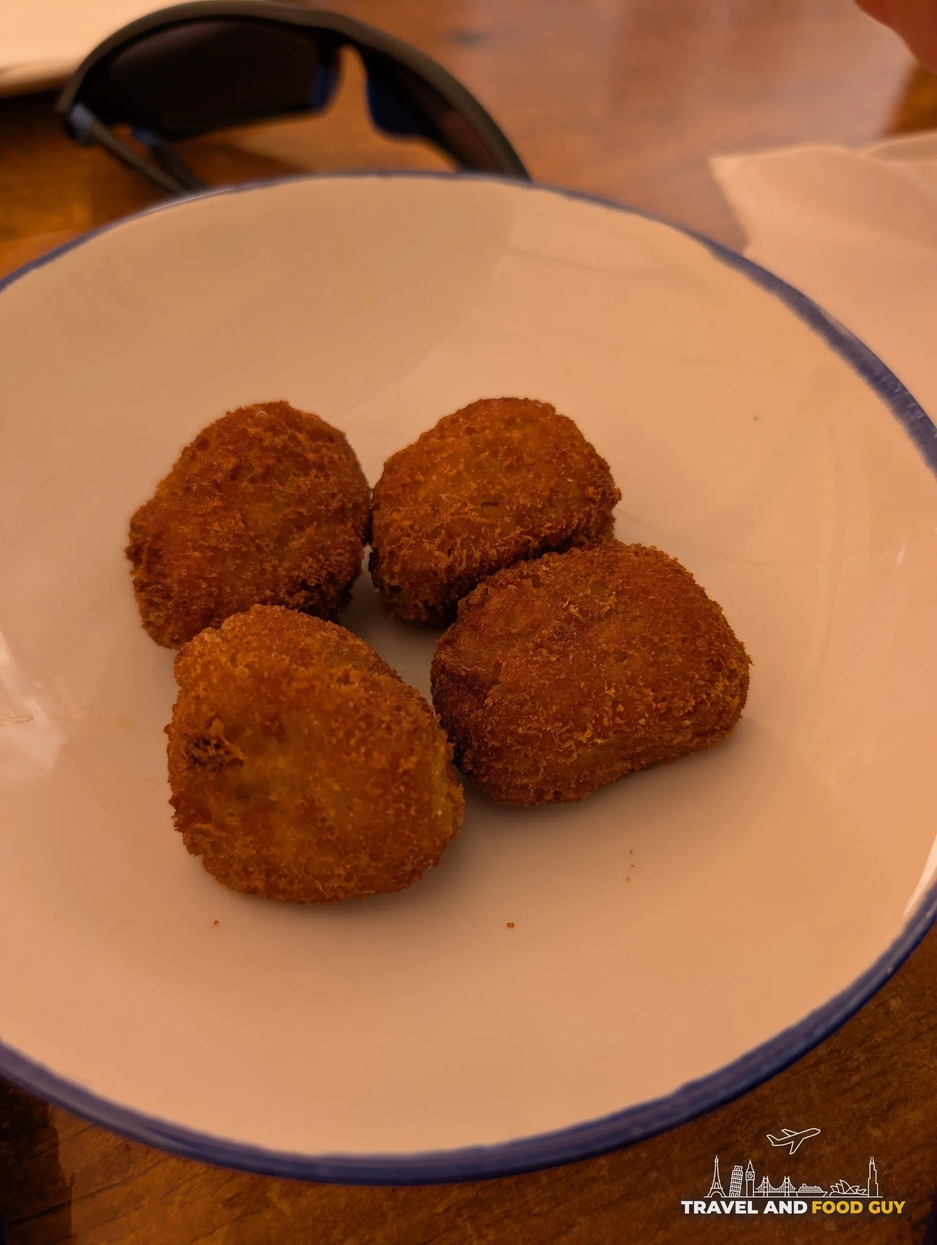 Four prawn croquettes in a white bowl with a blue rim at El Pimpi in Málaga