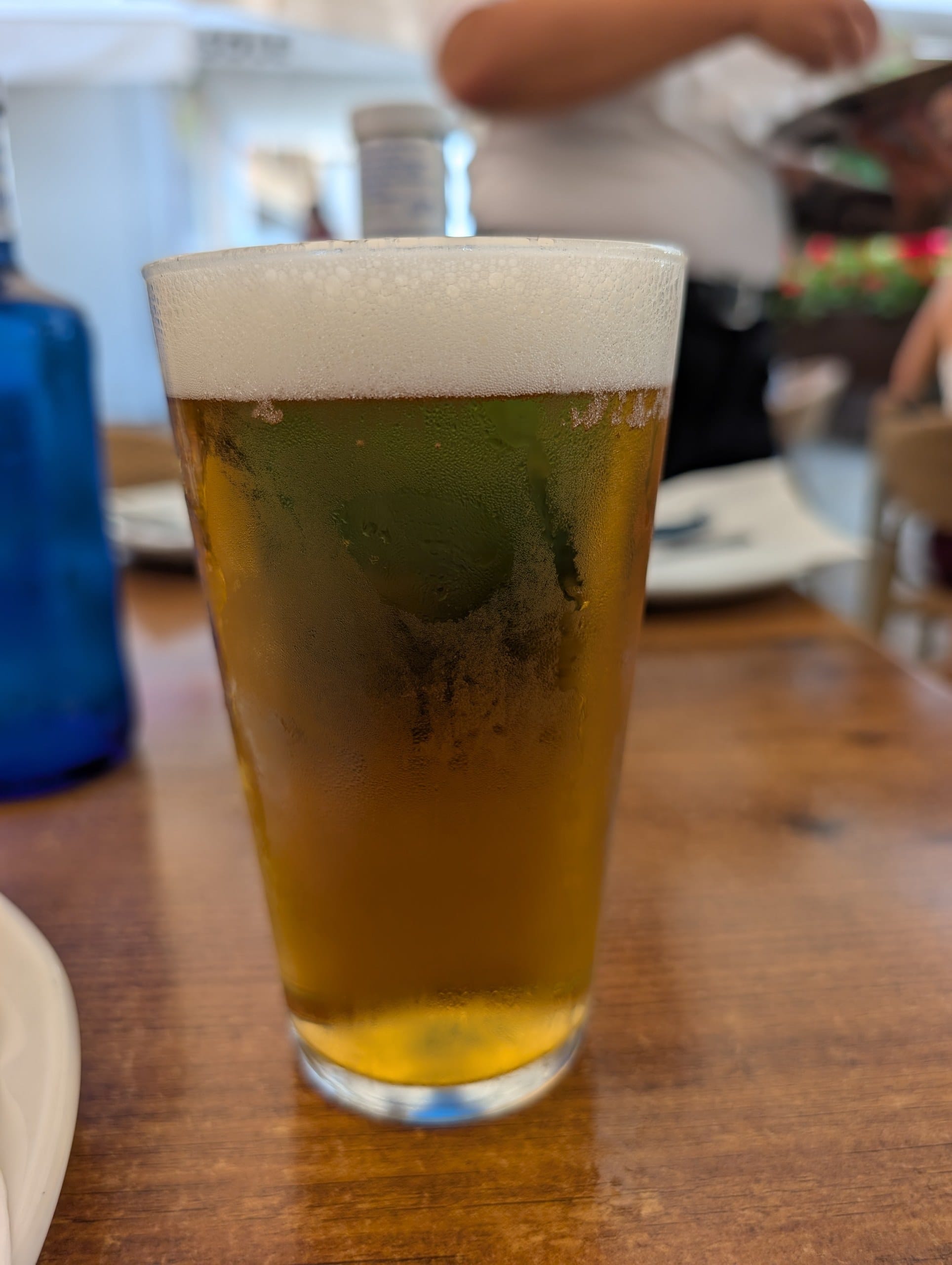 Cold draft beer in a branded glass on a wooden table at El Pimpi in Málaga