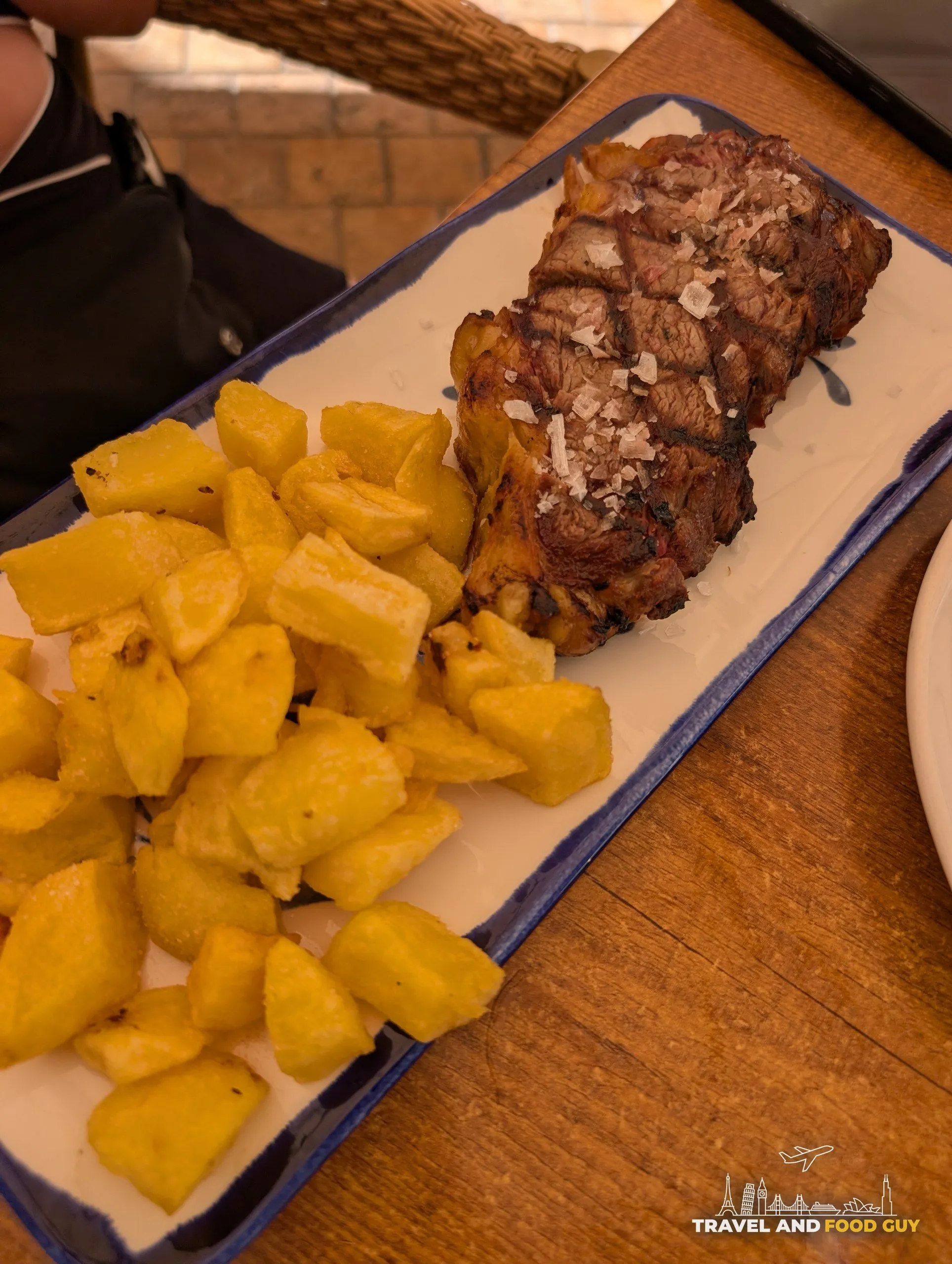 Aged beef sirloin topped with flake salt beside a plate of fried potatoes at El Pimpi in Málaga