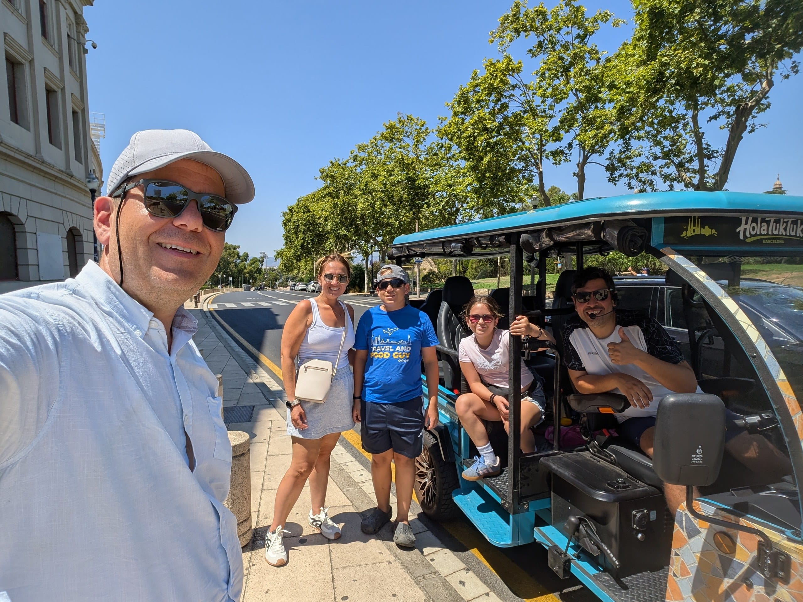 Alex, Vika, Josh and Emily with guide Leo beside the blue HolaTukTuk electric tuk tuk in Barcelona