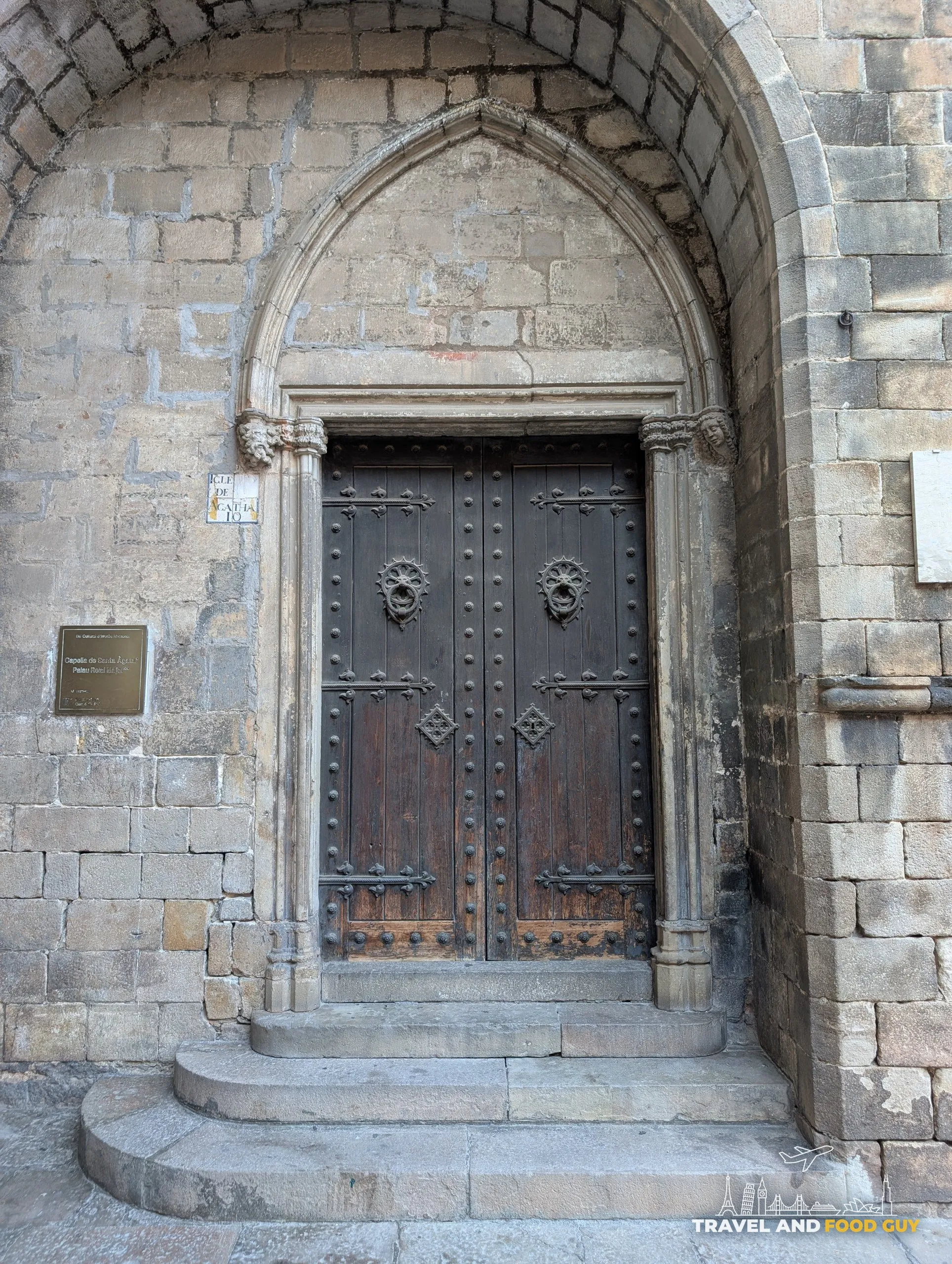 A Gothic arched doorway with a carved stone plaque beside it in the Gothic Quarter of Barcelona