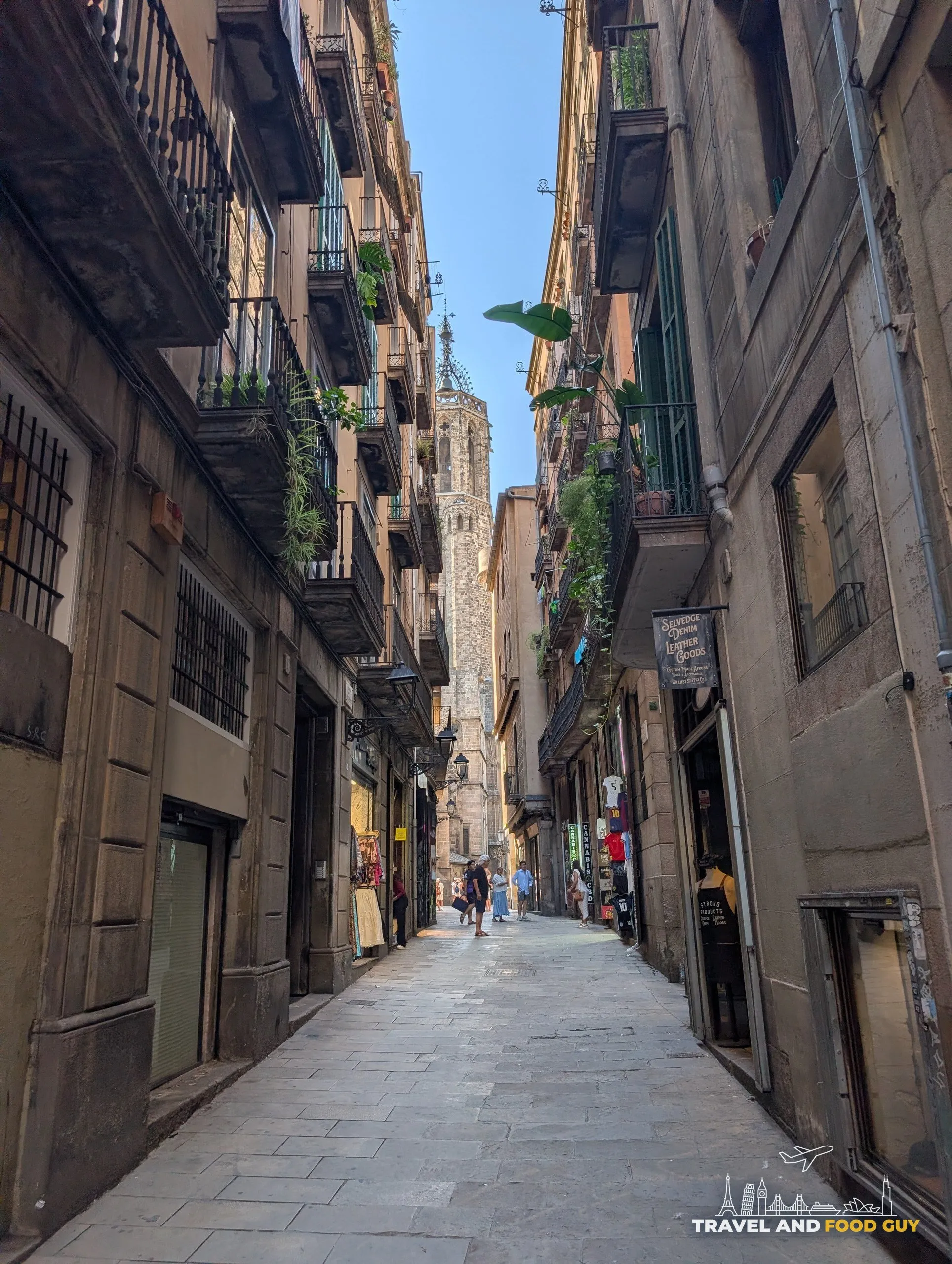 A narrow lane in the Gothic Quarter of Barcelona with the cathedral bell tower rising above the rooftops