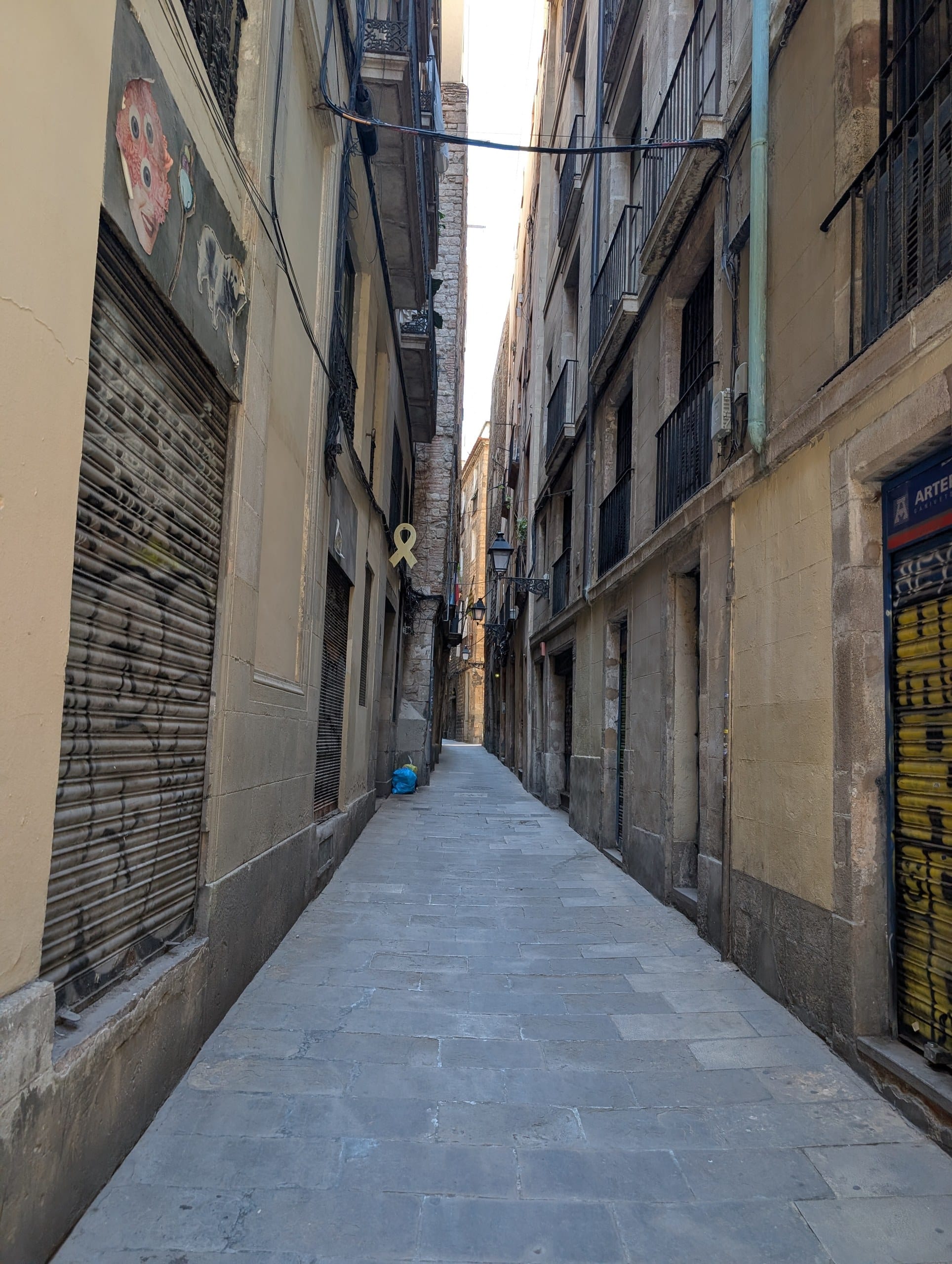 A shuttered lane in Barcelona barely wide enough for two people to pass
