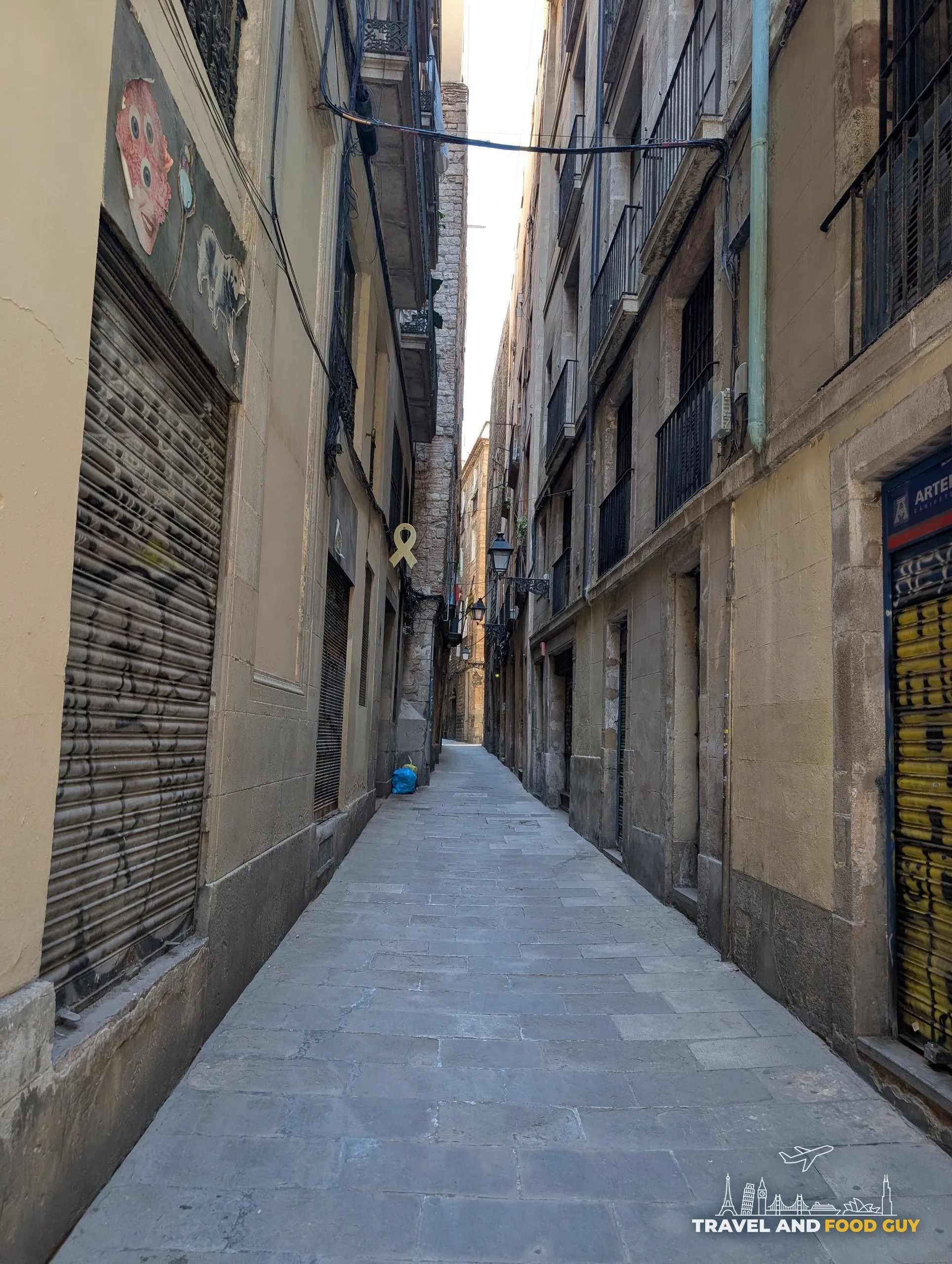 A shuttered lane in Barcelona barely wide enough for two people to pass