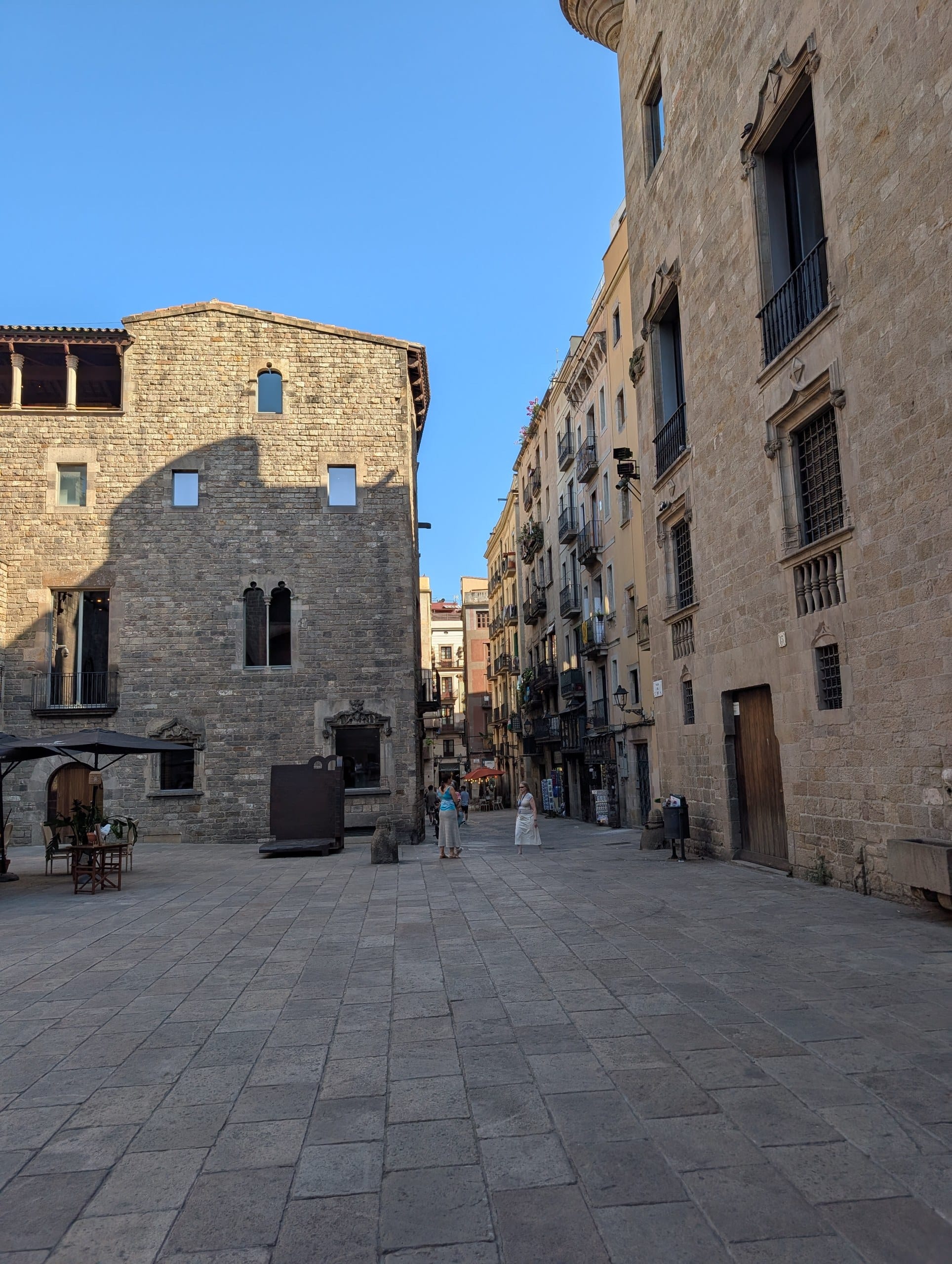 A quiet medieval stone square in the Gothic Quarter of Barcelona in low afternoon sun