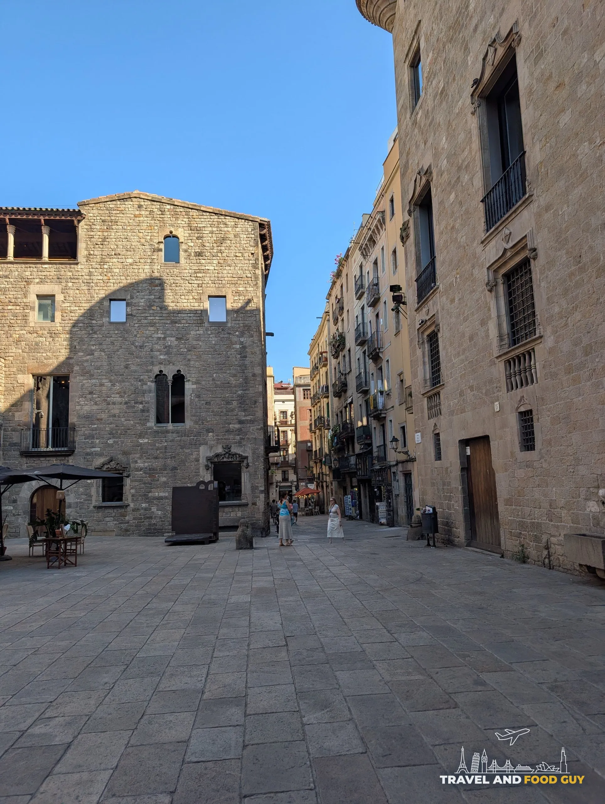 A quiet medieval stone square in the Gothic Quarter of Barcelona in low afternoon sun