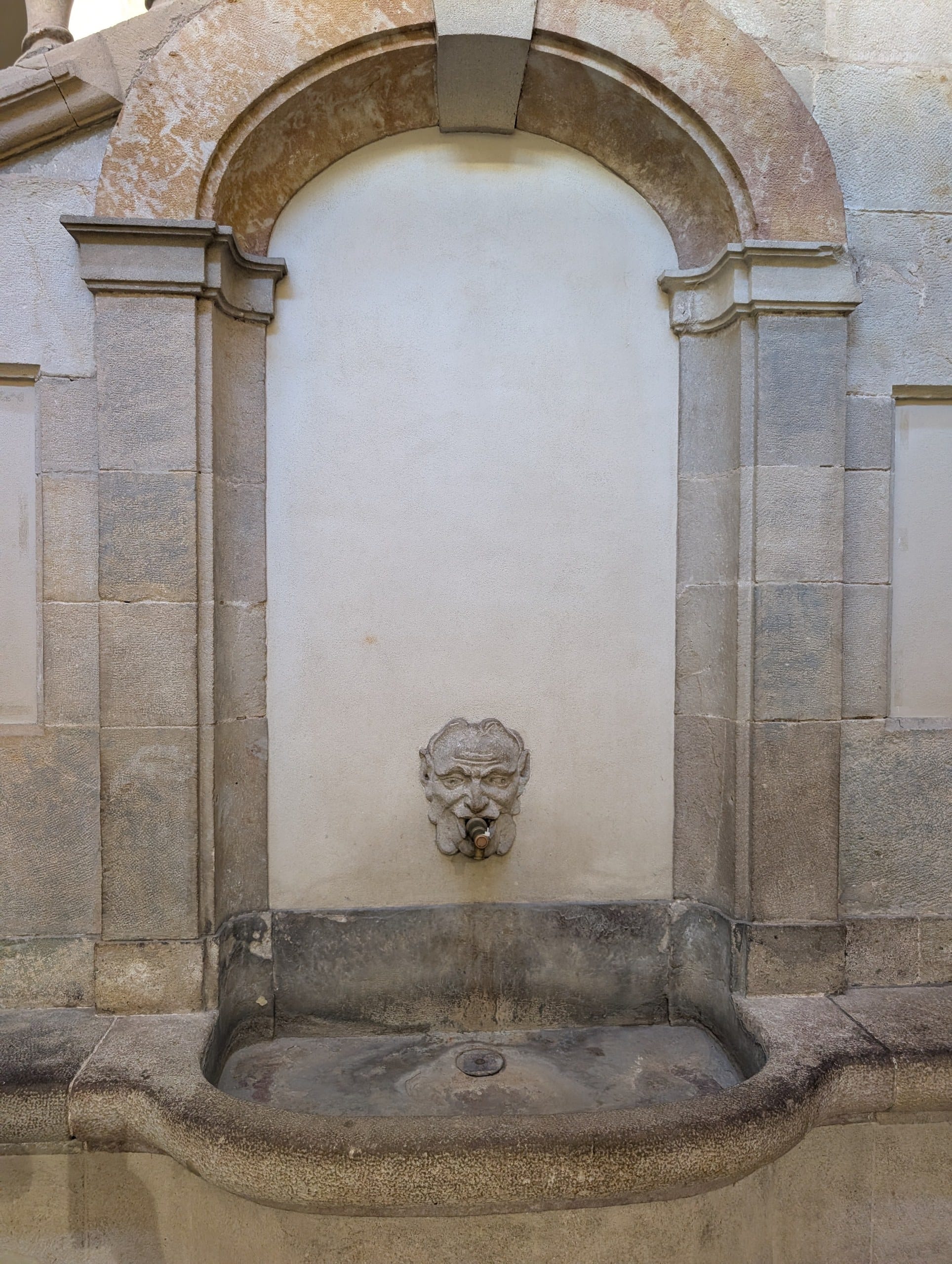 A carved stone wall fountain set into a building in the Gothic Quarter of Barcelona