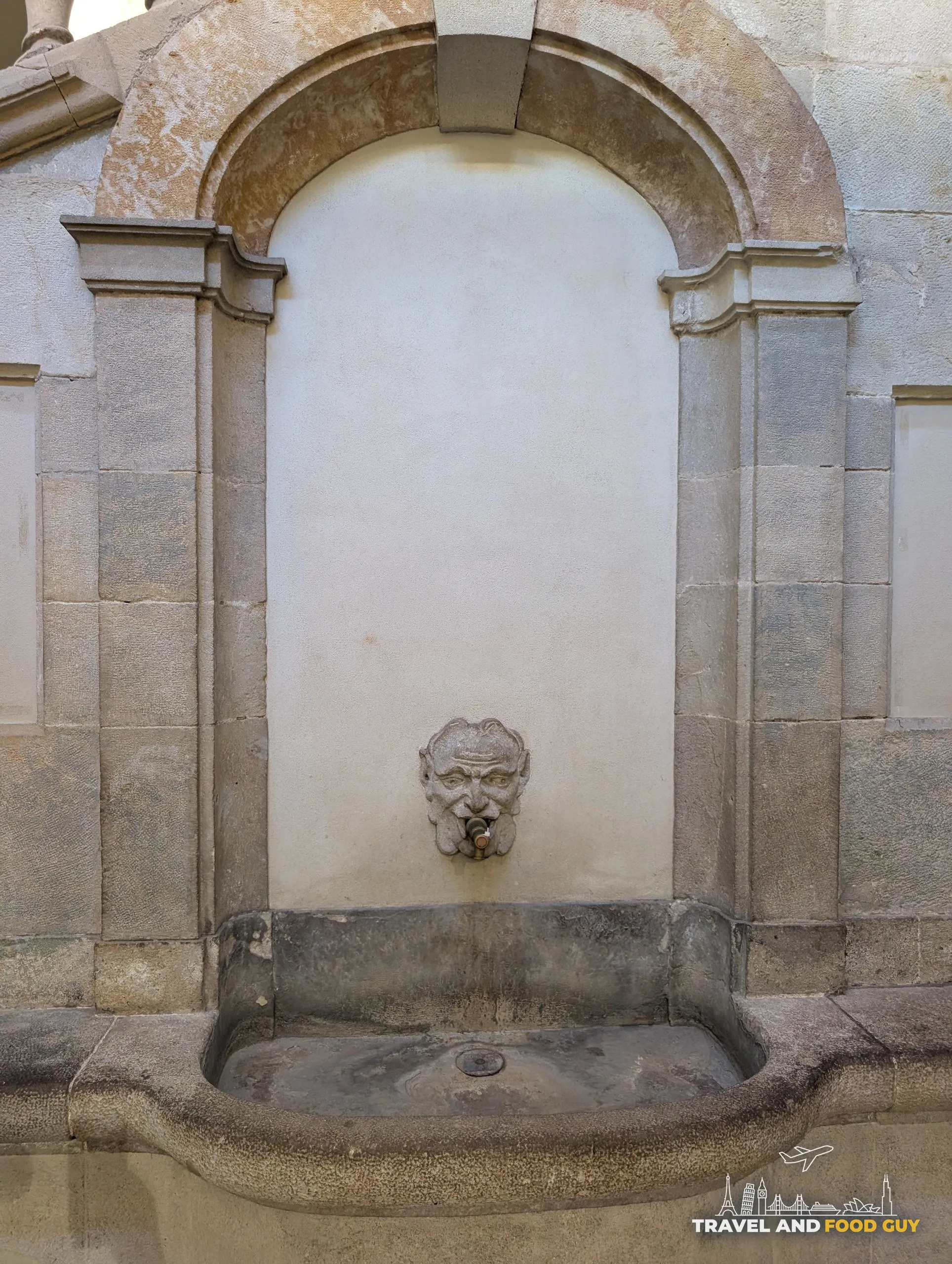 A carved stone wall fountain set into a building in the Gothic Quarter of Barcelona