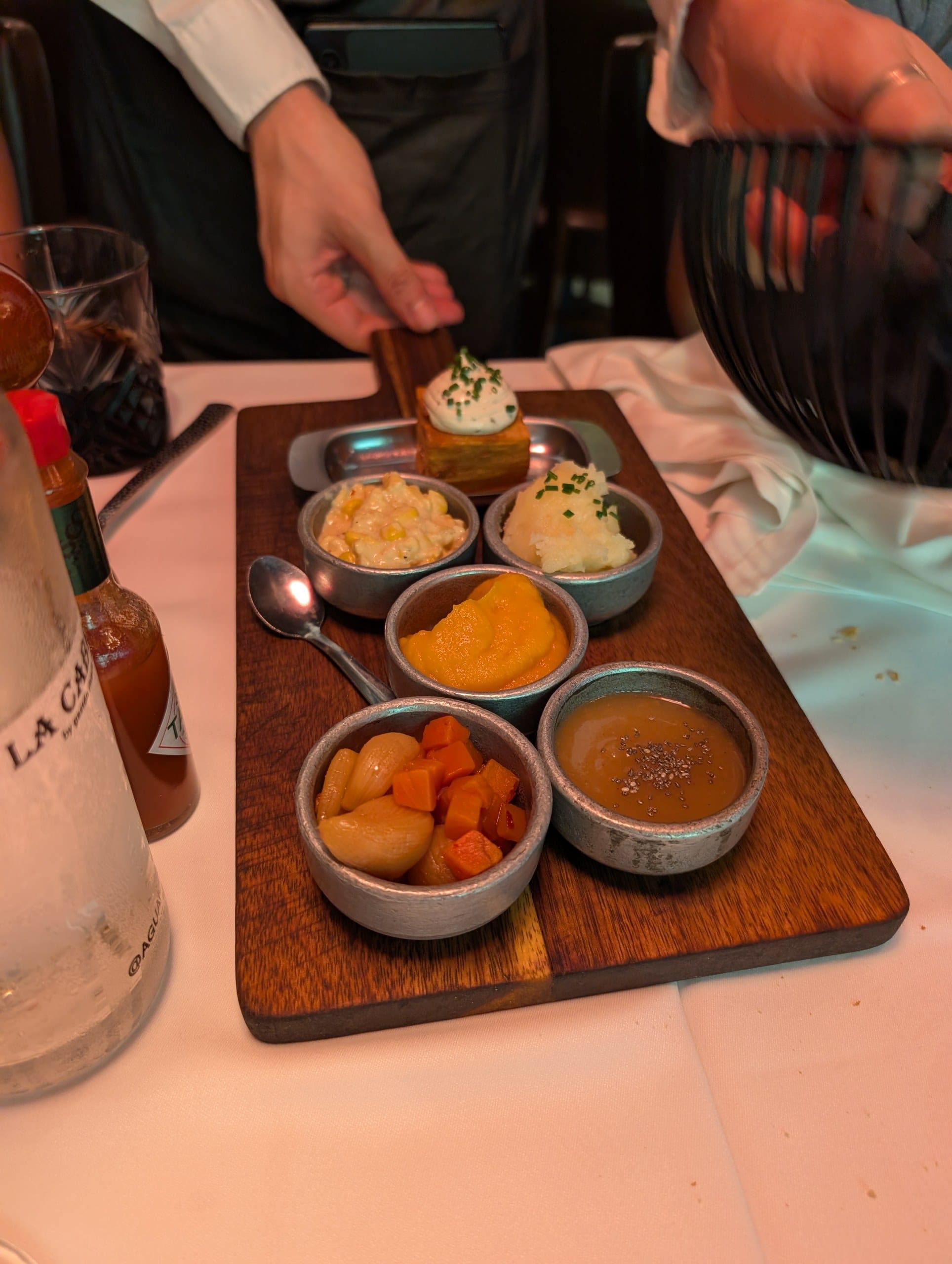 A waiter setting down the complimentary board of warm sides at La Cabrera Barcelona
