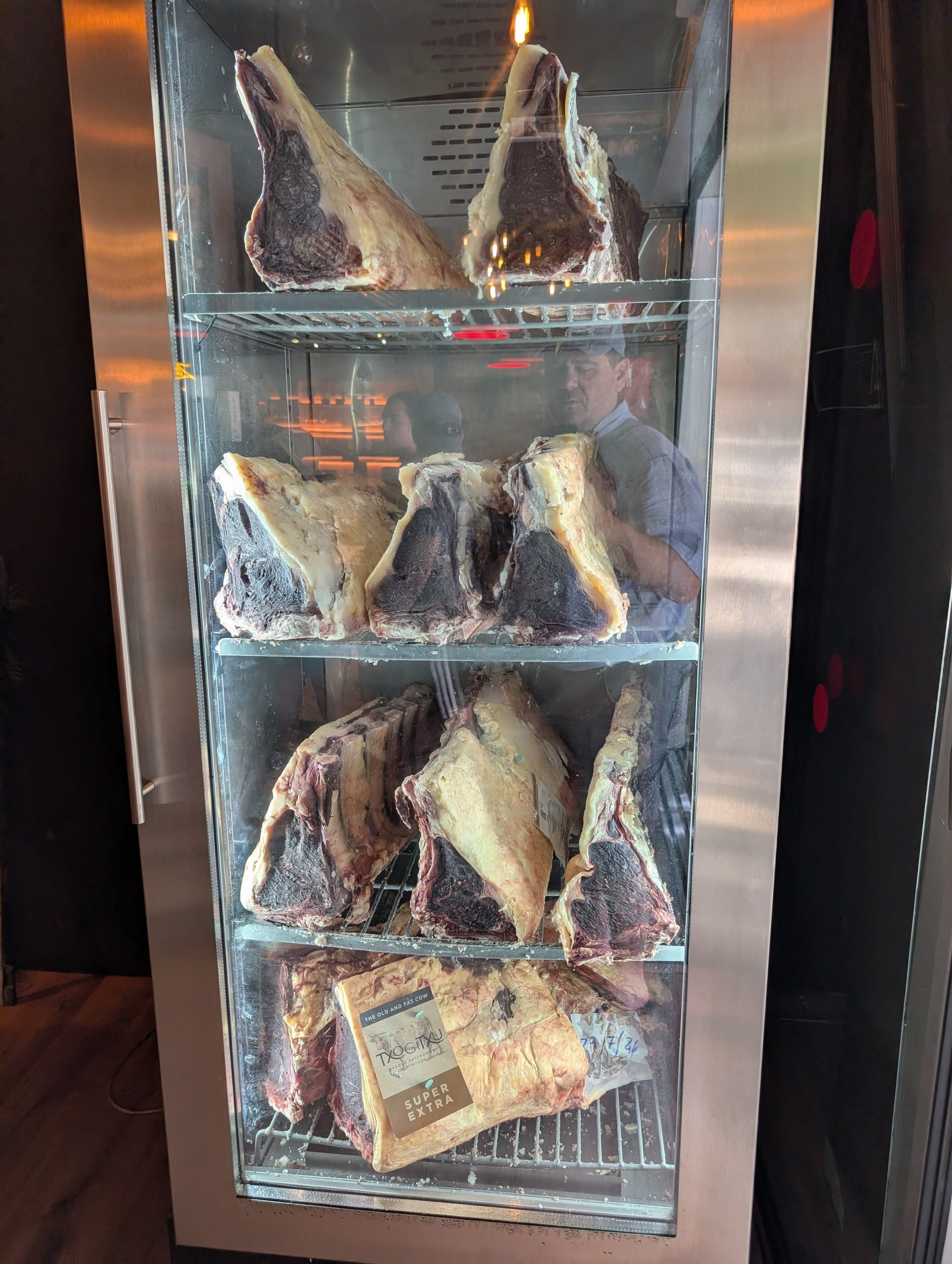 Bone in cuts of beef aging in the glass cabinet inside the door at La Cabrera Barcelona