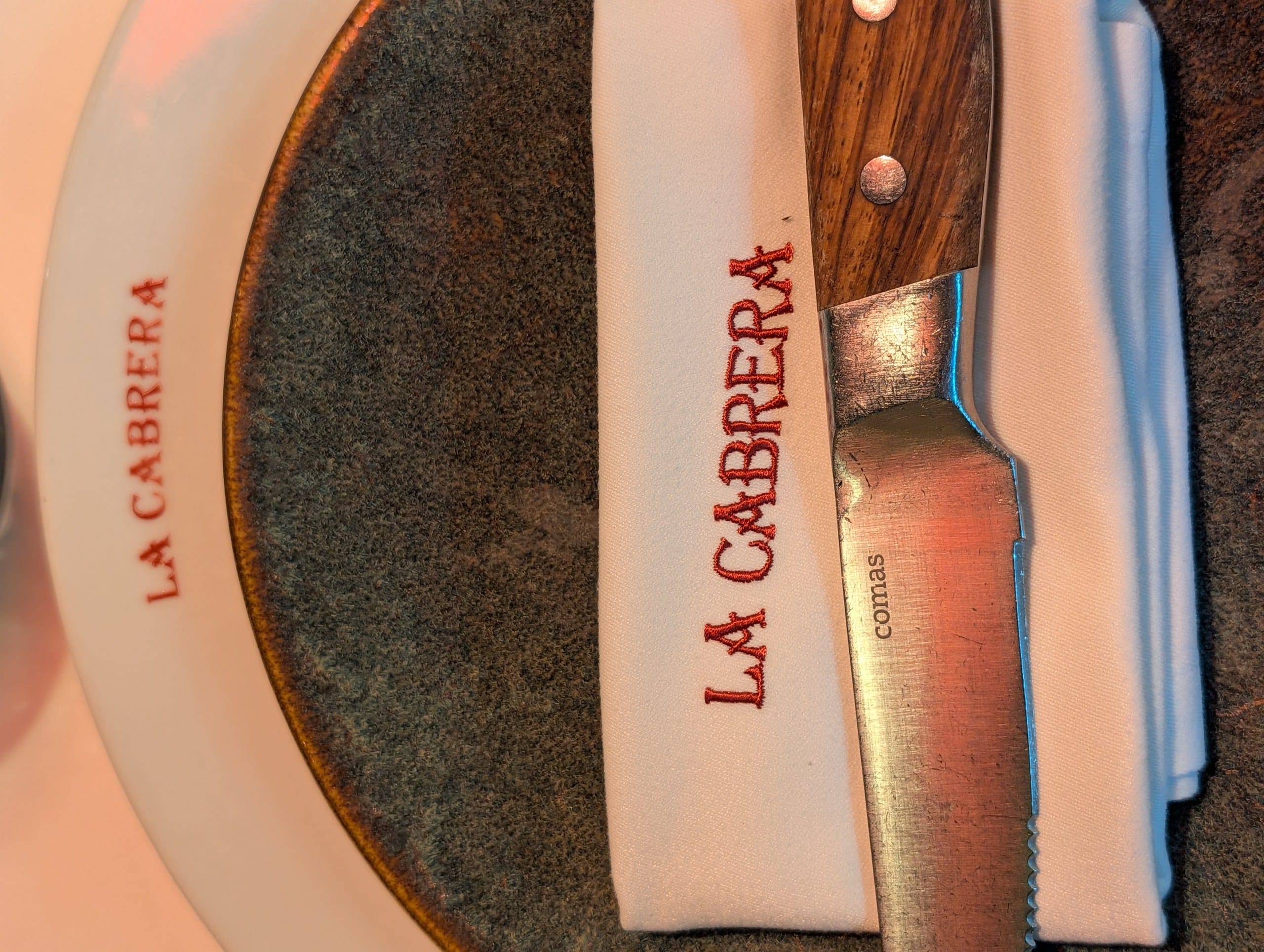 A branded napkin and wooden handled steak knife already set on the table at La Cabrera Barcelona