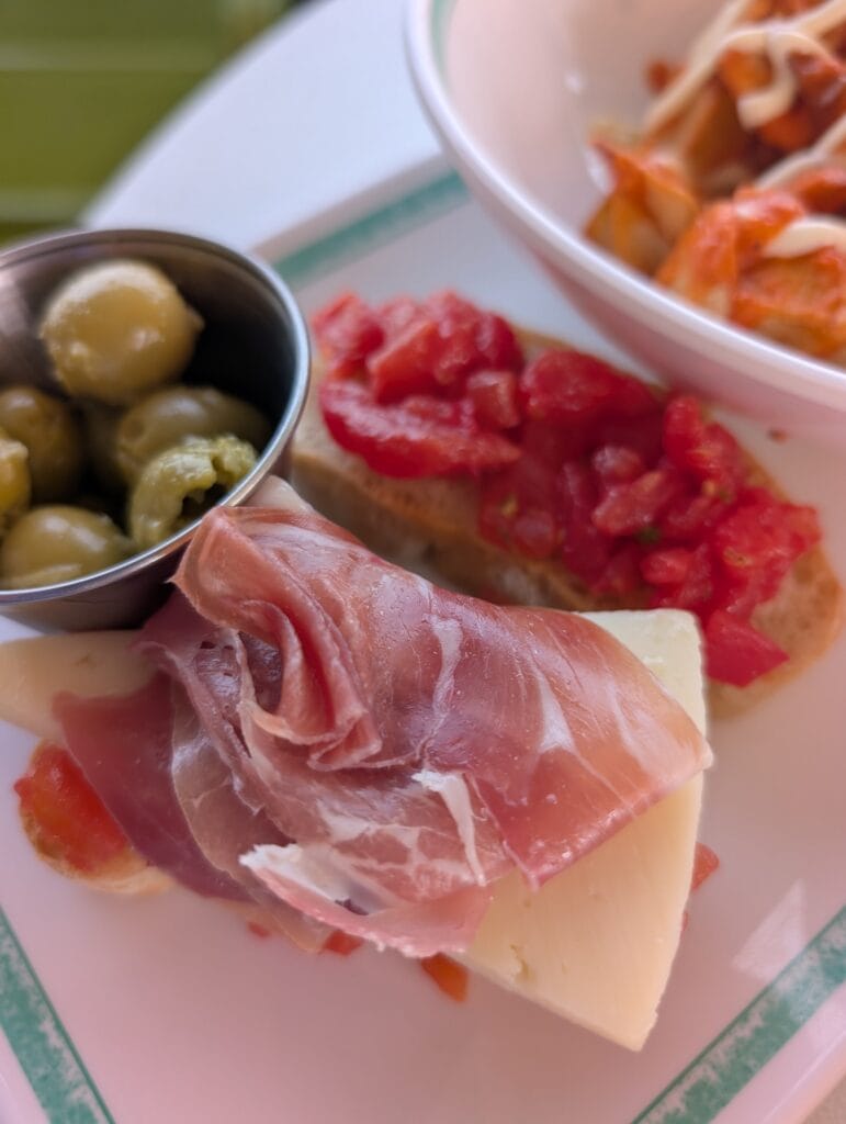 Jamon draped over manchego on pan con tomate, with marinated Spanish olives and the patatas bravas bowl, from La Espanola in the AquaDome Market.